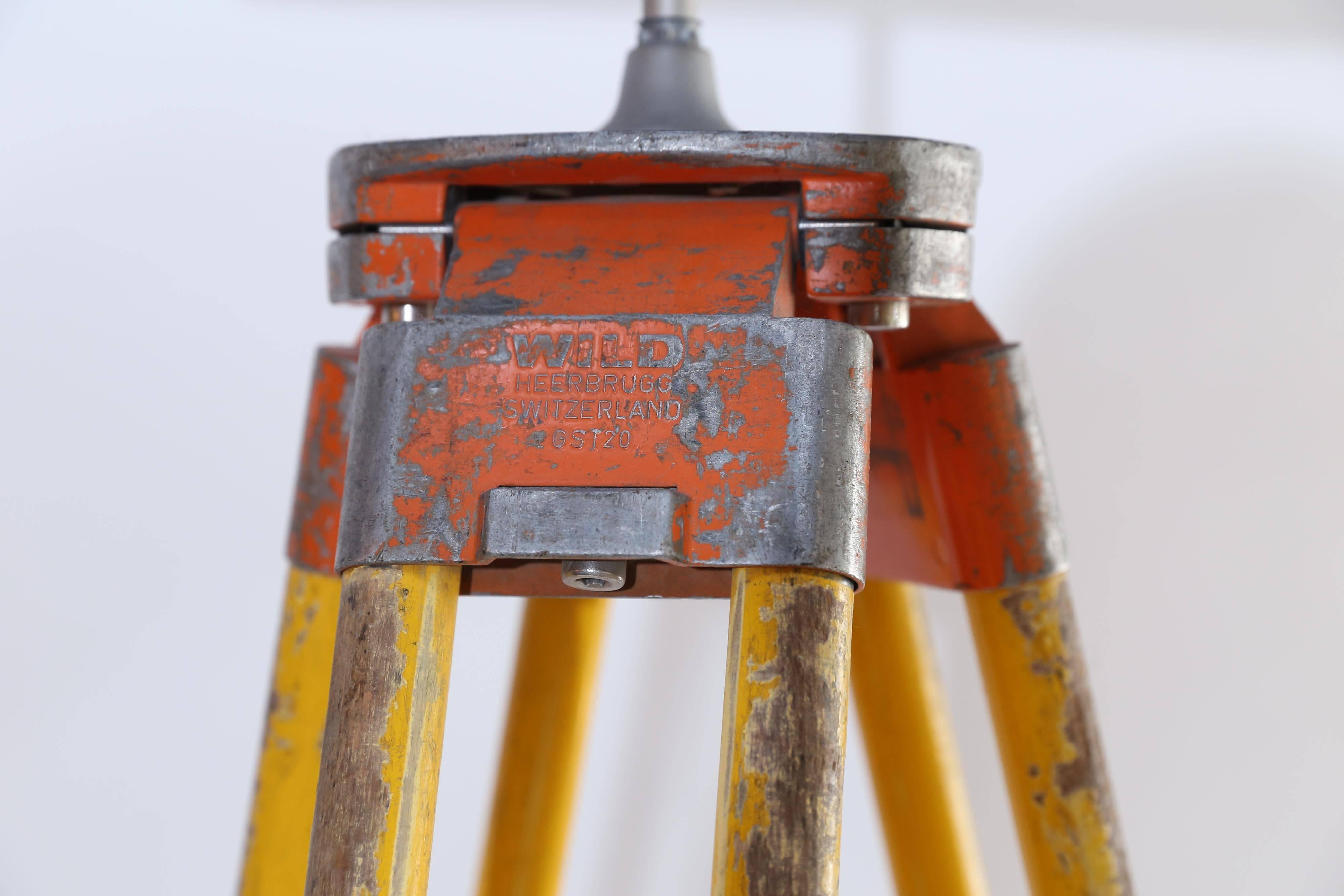 A vintage surveyor's tripod from the Wild Heerbrugg Company of Switzerland made into a versatile floor/table lamp. Made of alpine beech with original bright yellow paint, the tripod has external wiring with a yellow rocker switch suspended 18 inches