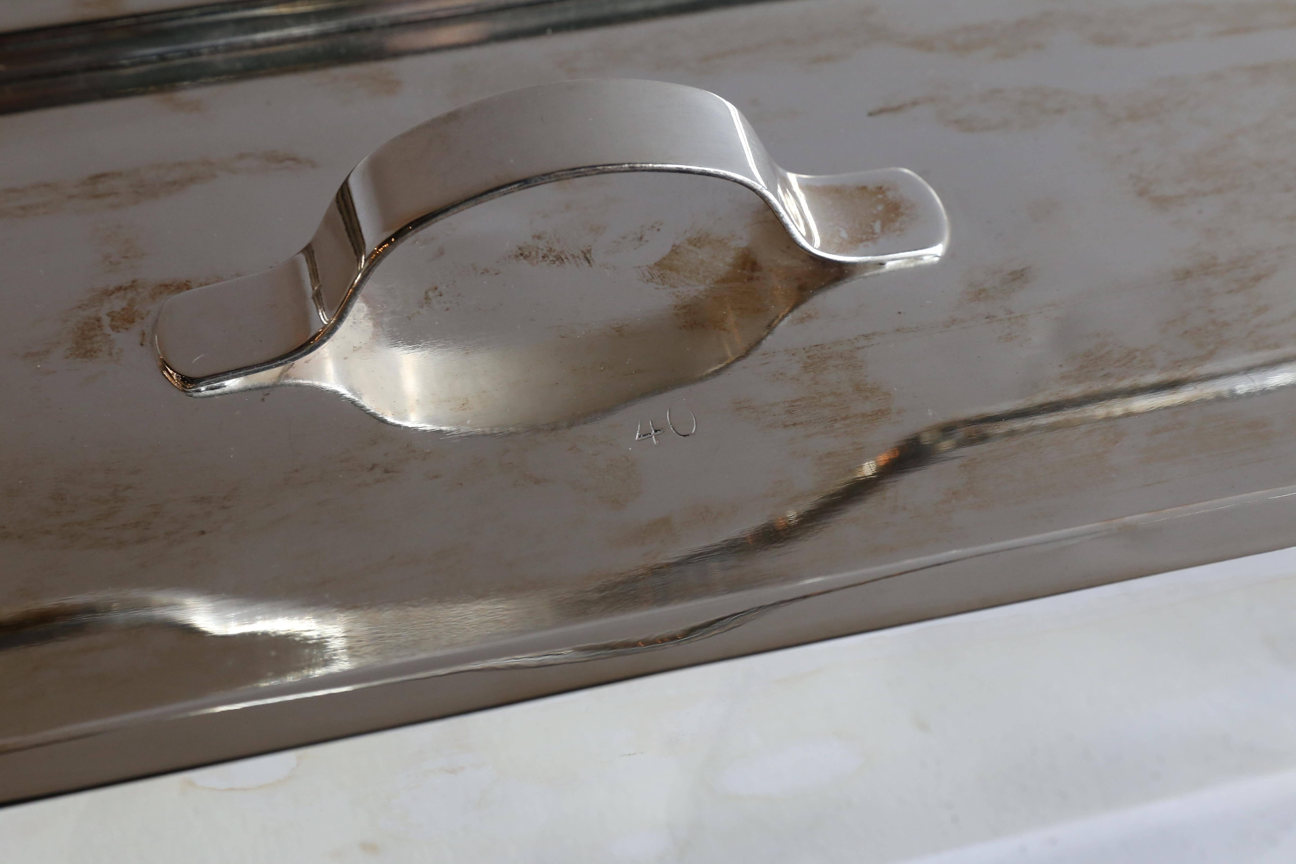 A vintage fish poacher with rack from France. Made of aluminium, this wonderful old piece of hotel silver has been recently restored with a new triple plating of silver. One minor dent on the edge of the lid. Polishes to a perfect finish.