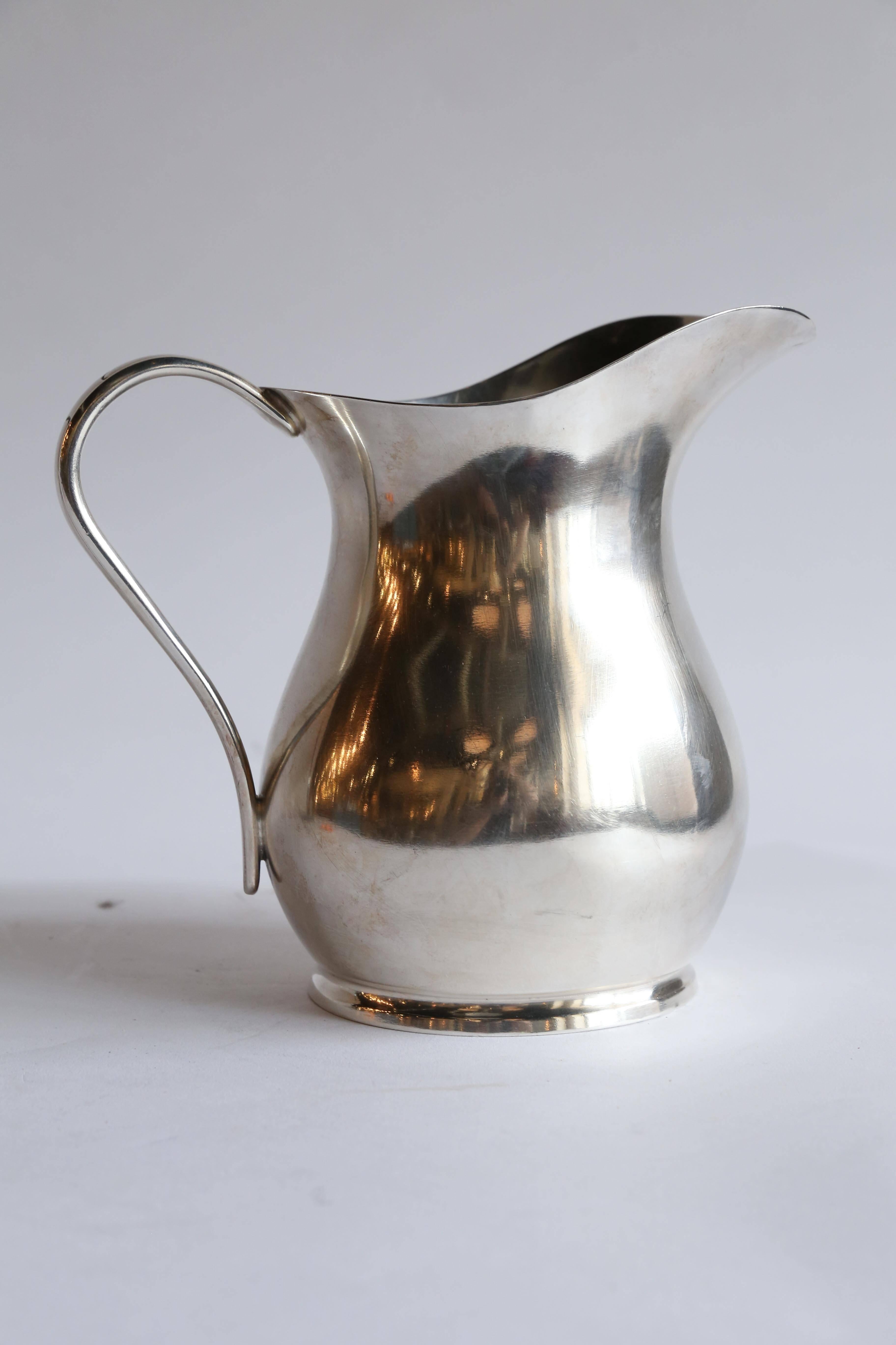 A World War II era silver soldered pitcher made by Reed and Barton for the US Navy. With a Classic shape and a quietly decorated handle, these pieces were made extra dense and heavy so as not to spill when the ship was under sail. Marked Reed &