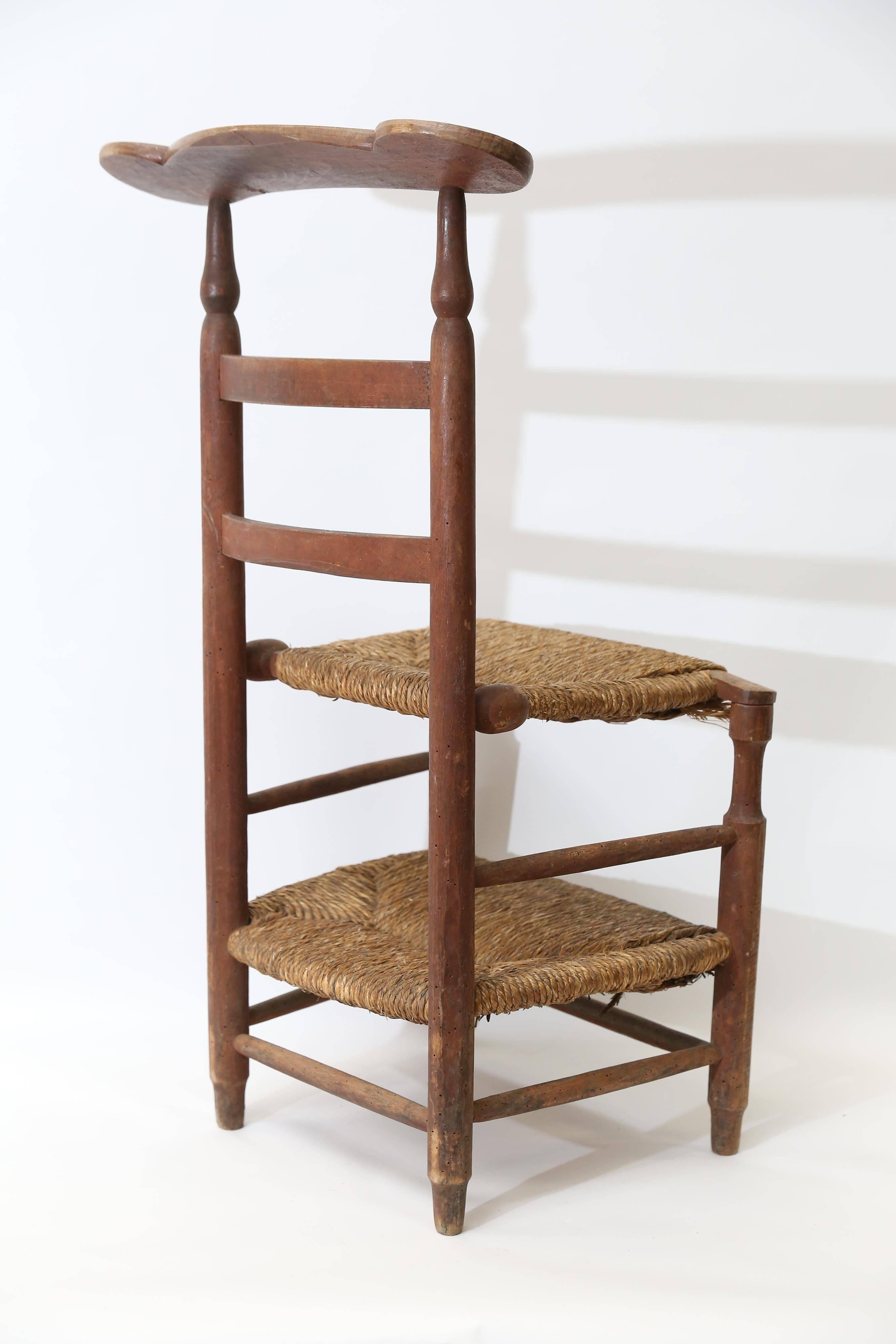 A charming rustic prie dieu from France with turned legs and back. In a medium dark stain and with rush seats, the back armrest has the initials AA carved into it. The rush is in good condition with only the expected few broken strands and needs no