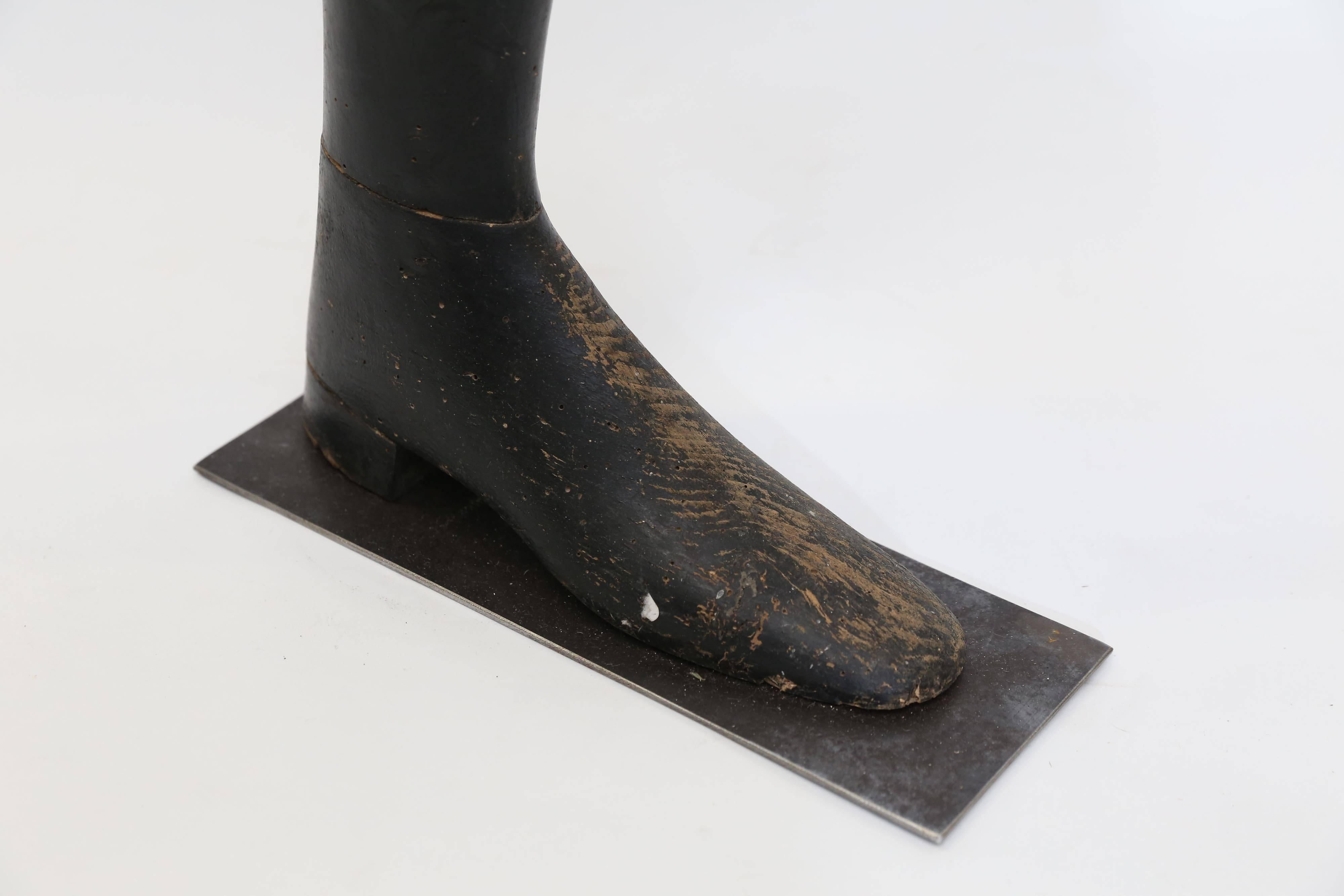 A black wooden shoe form from France on a custom metal base. A curiosity on it's own, it's the perfect door stop or bathroom paper holder. Fun and interesting.