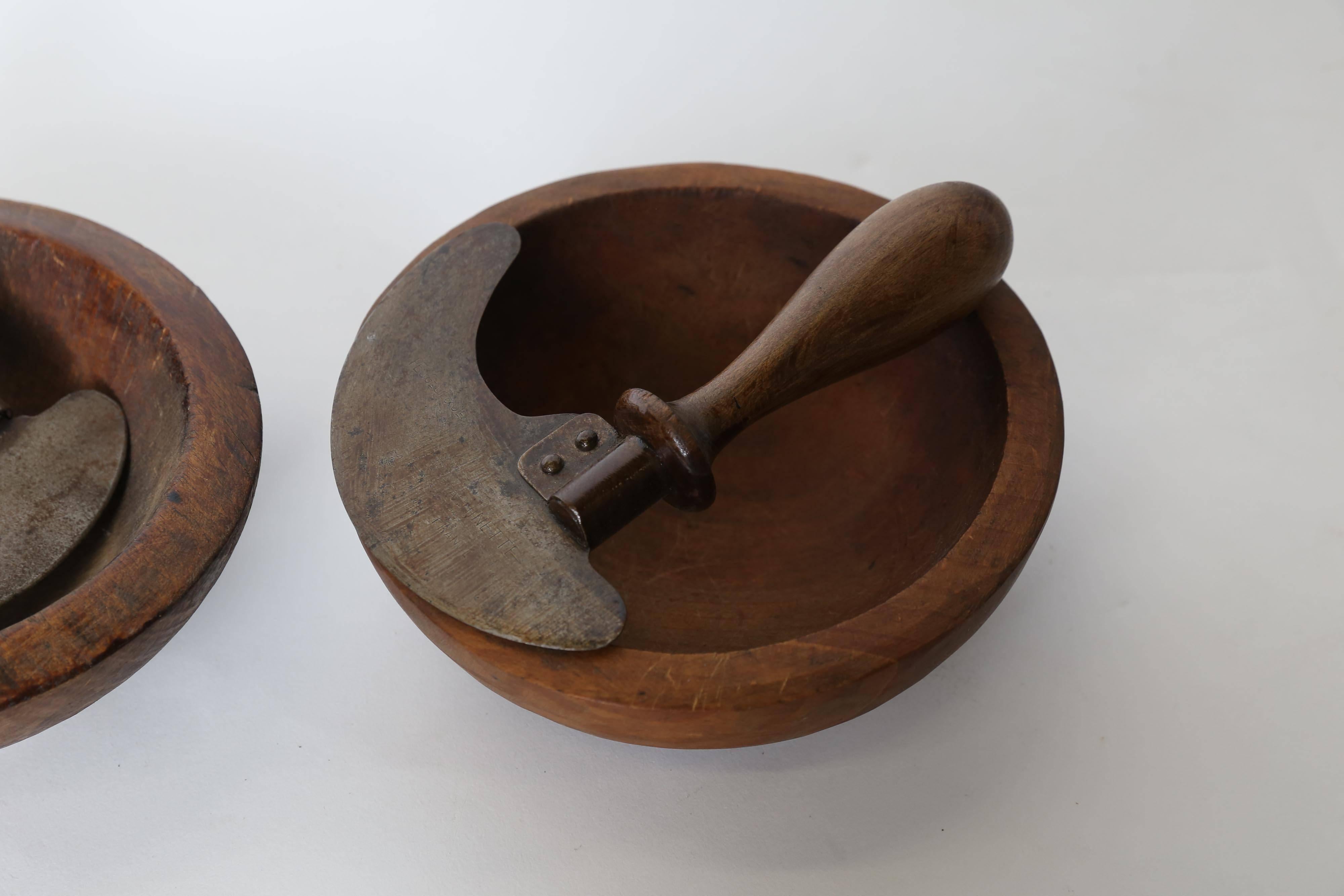 Herb cutter and olive wood bowl from France. The chopper each has an upright wooden handle attached to a crescent shaped steel blade with a wraparound riveted metal strip. The lathe turned bowls have no splits or cracks. The blade has an aged patina