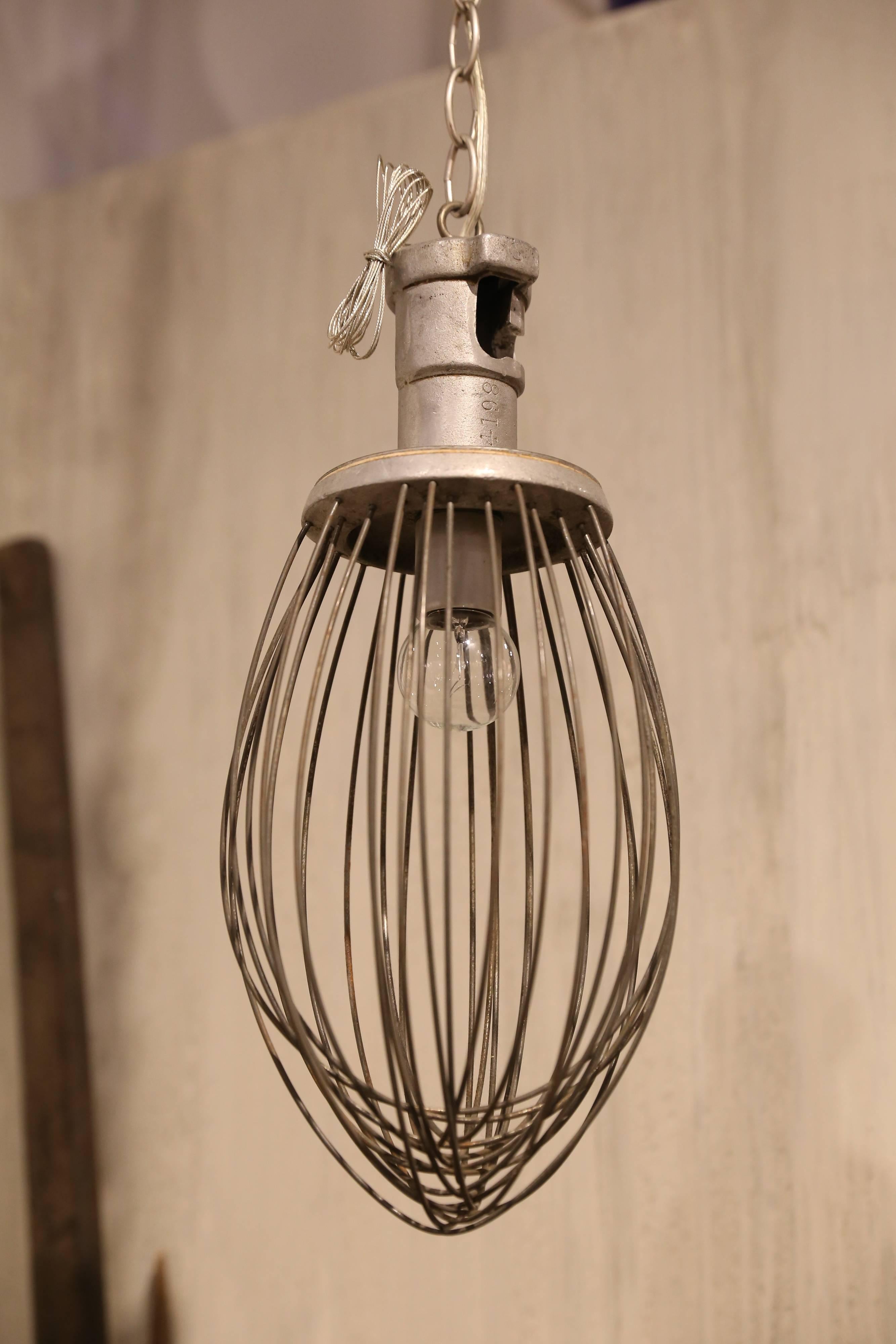 A commercial bakery whisk found in France takes a new turn as a pendant light fixture. With approximately 40 inches of chain and a 5 inch tin canopy, this one is just plain fun.
