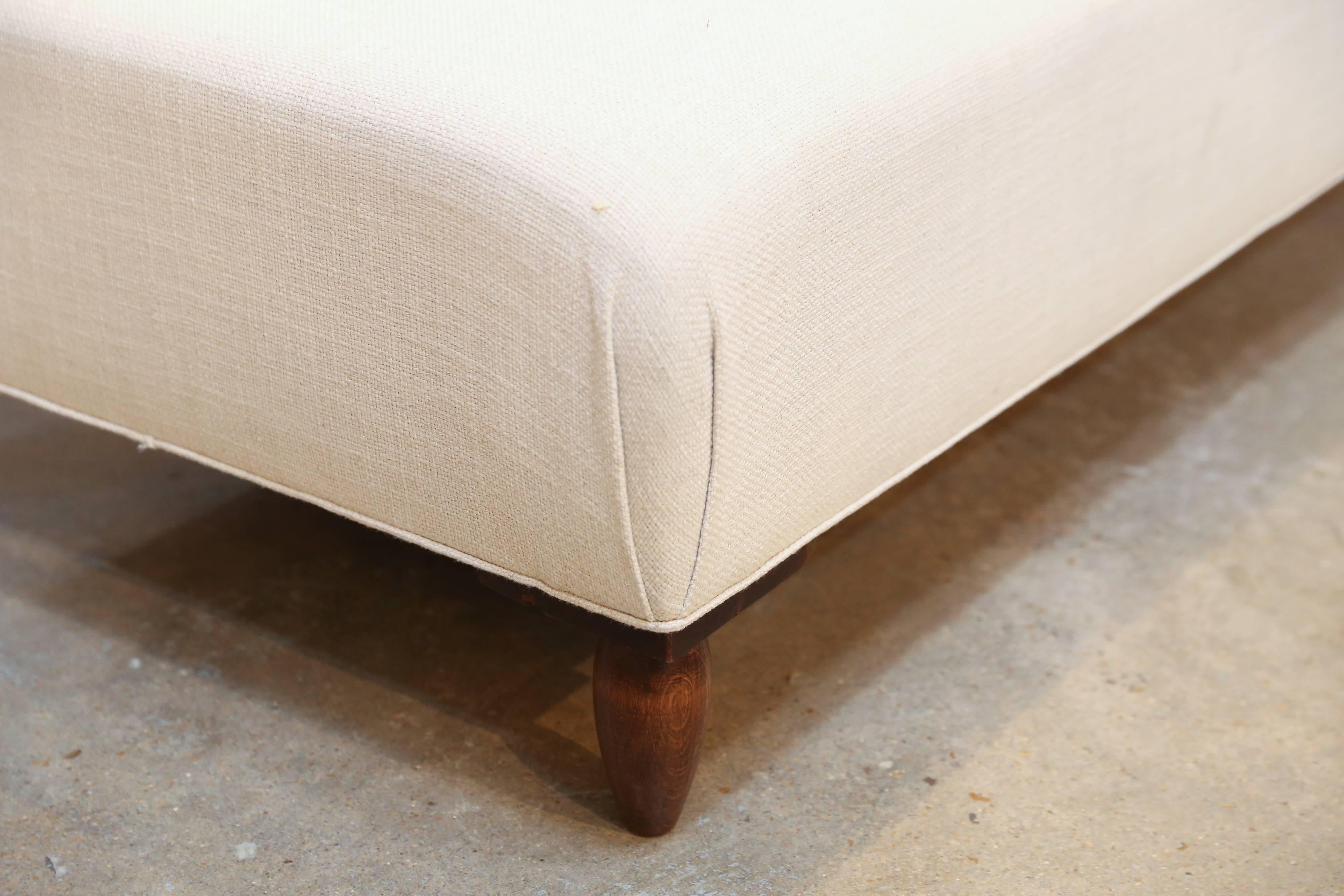 A large ottoman found in France with midcentury turned-wood feet, newly upholstered in an off-white linen blend. Extra seating or a great coffee table.