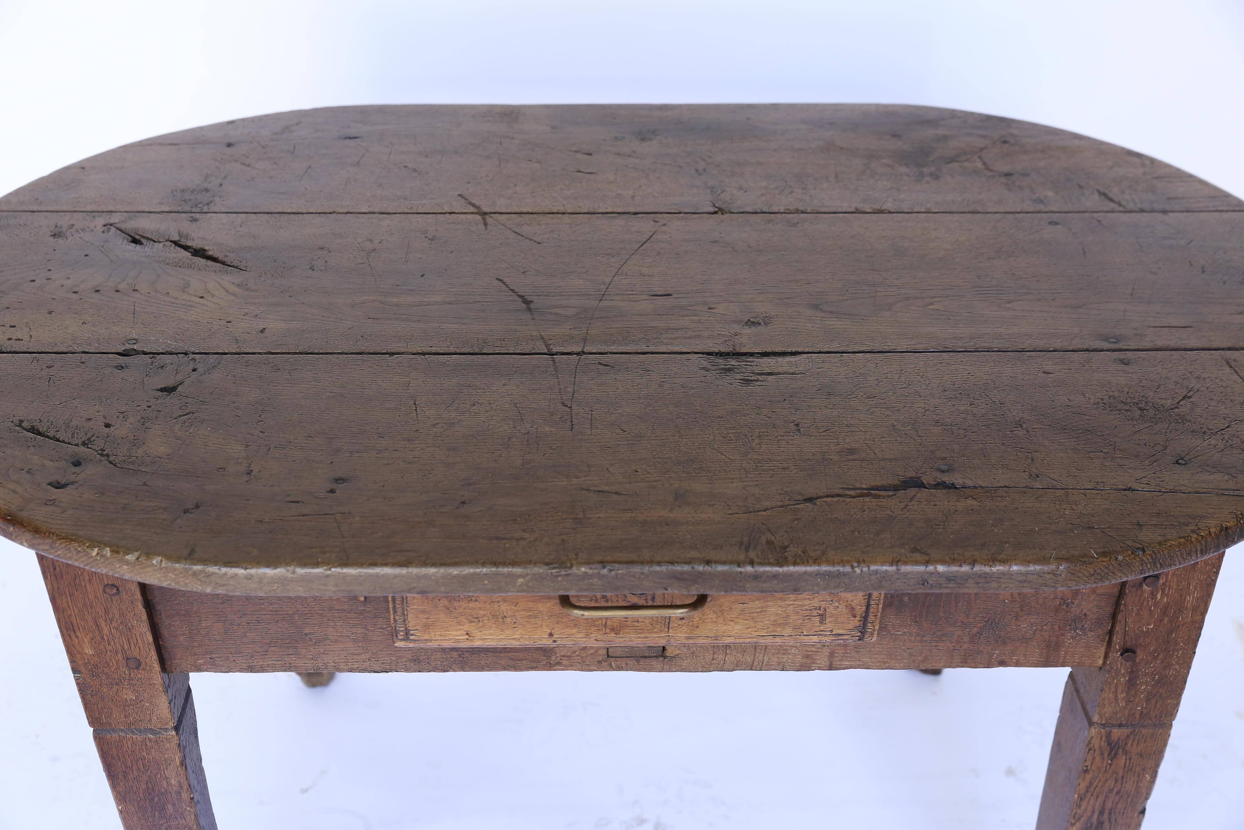 An oval table with one drawer from France, circa 1880. Beautifully handmade, it's all about the look and feel of the wood which has a lovely patina and interesting surface anomalies. The single drawer has a simple wire pull. A delightful piece with