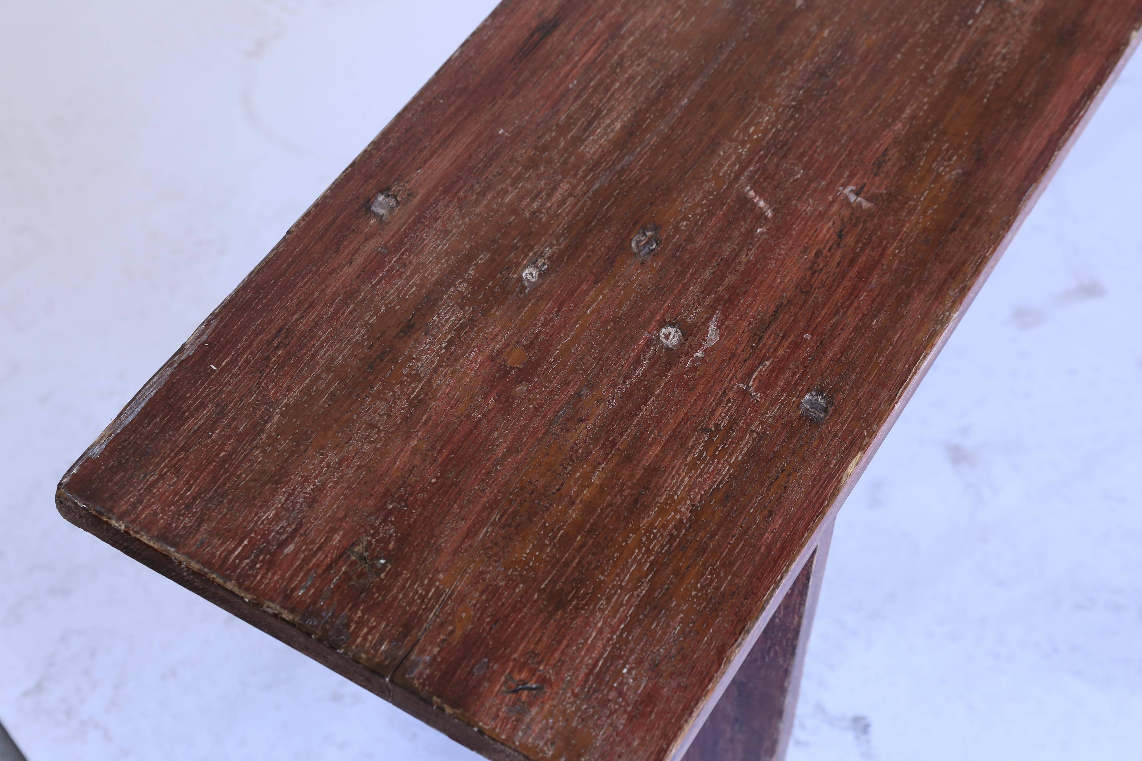 A 9 foot long wooden bench with a red oak stain from France. Solid and sturdy. Two are available.