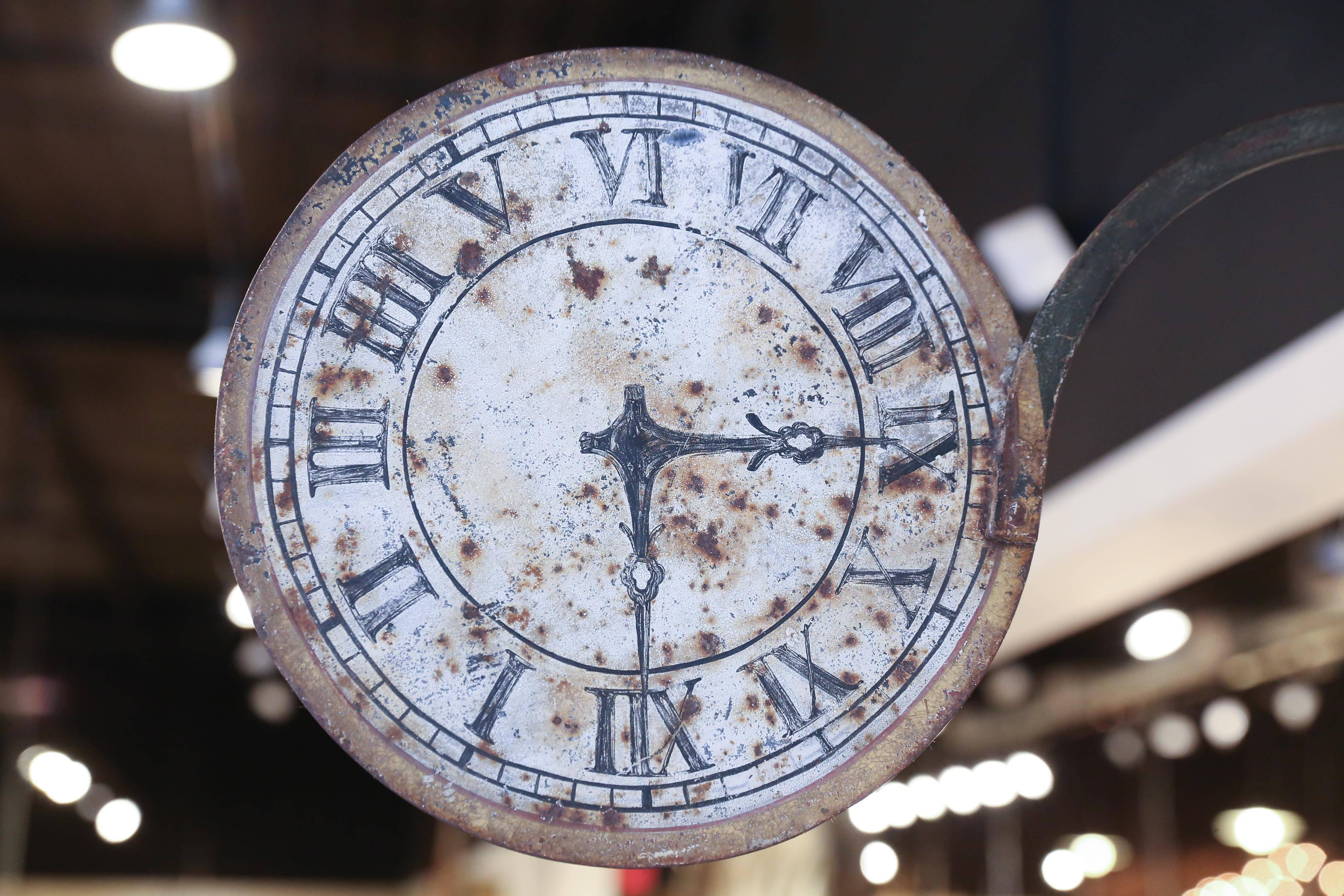 A unique and utterly charming sign from a clockmaker's shop in France. Made of iron and sheet metal, the 12 inch clock face is supported on a 28 inch iron bracket with a leaf embellishment. One side of the sign is beautifully aged and worn while the
