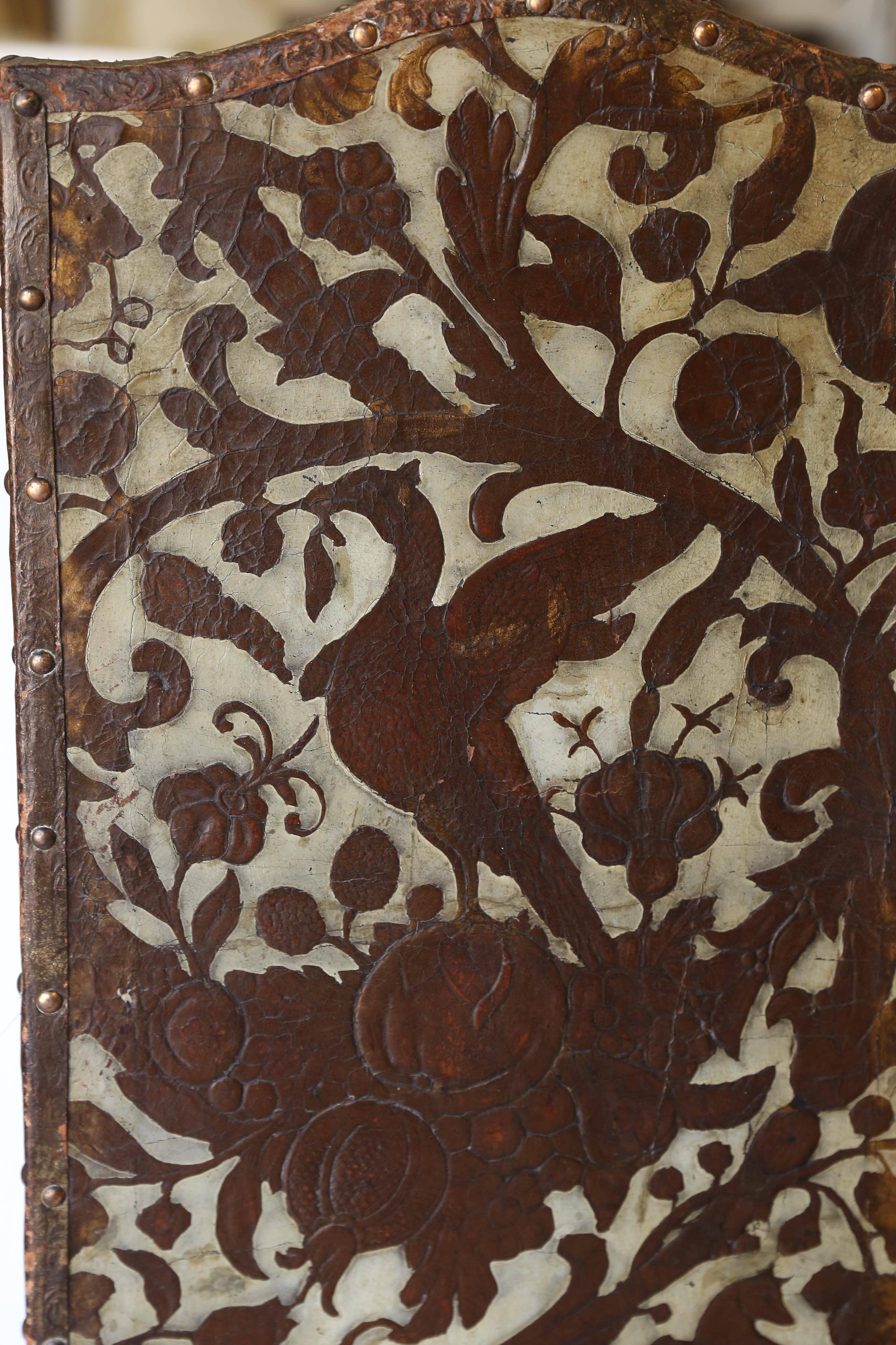 Monkeys, foxes, and birds climb through the vines and flora of this exquisite antique leather screen from Italy. With painted areas still almost fully intact, there are also areas of the original copper gilding remaining. Attached to the frame with