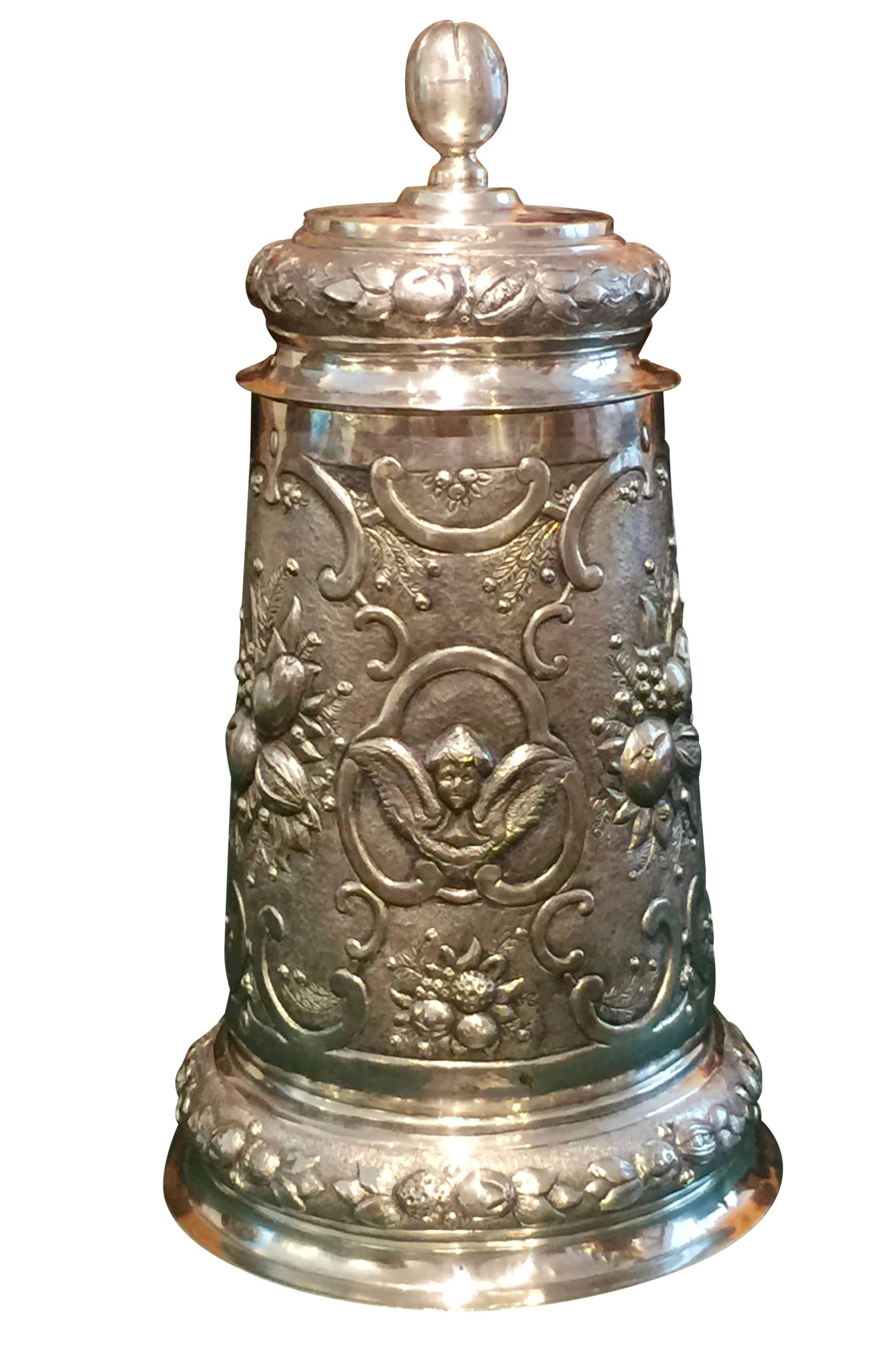 Historicism Lids, silver 800. Conical vessel body on slightly flared and beaded stand. Cover with hinge. Lid crown in the form of a bud. Earshekel rich relief decor of fruit buckets and winged angels. Hanau, circa 1870. (circa 2,2 pounds/35,3