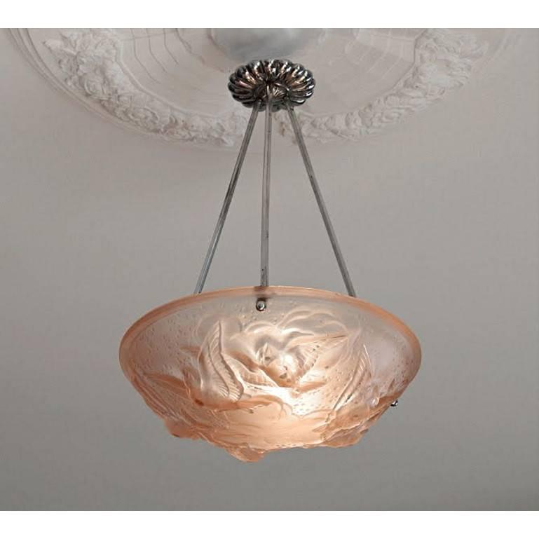 French Art Deco chandelier by Muller Frères, Luneville, late 1920s. Pink frosted molded glass shade showing six birds in the sky (clouds), hung on its nickel-plated metal fixture. Signed 