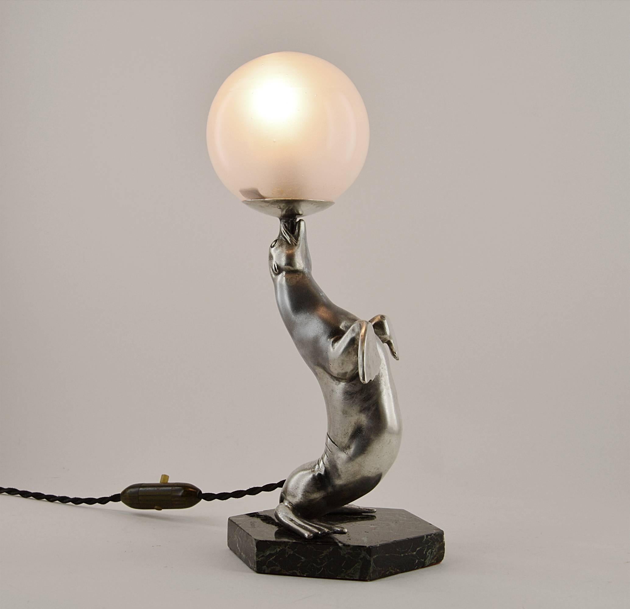French Art Deco table lamp by Louis-Albert Carvin, France, 1930s. silver plated spelter sea-lion playing with a ball (opaque glass shade). On a black and green marble base. Will be delivered wired for your country (US, EU, Australia, etc).

 