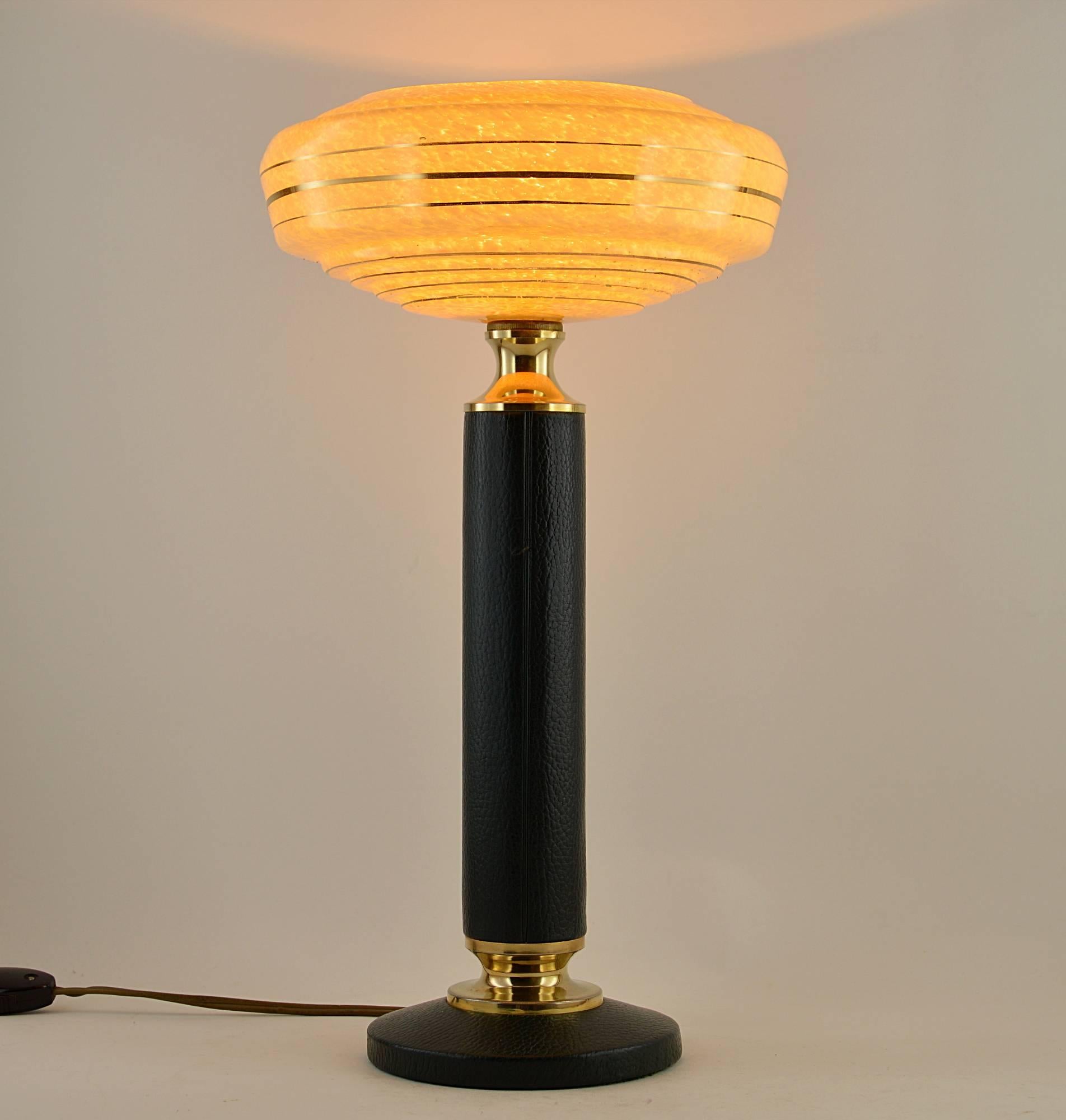French Art Deco leather table lamp in the style of Jacques Adnet, circa 1940. A superb large glass shade flecked with yellow wearing golden concentric stripes on a bottle-green leather and brass base. Delivered wired with a B22 socket for your