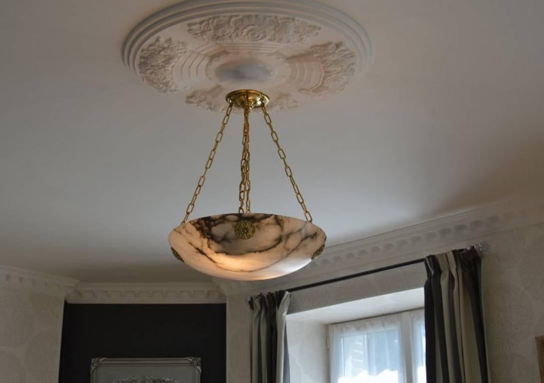 Large French Art Deco chandelier, circa 1930. Large thick alabaster shade hanging from its original solid bronze fixture. Old alabaster cannot be compared to new one. Old alabaster has veins. Sometimes they can be mistaken for cracks. But they are
