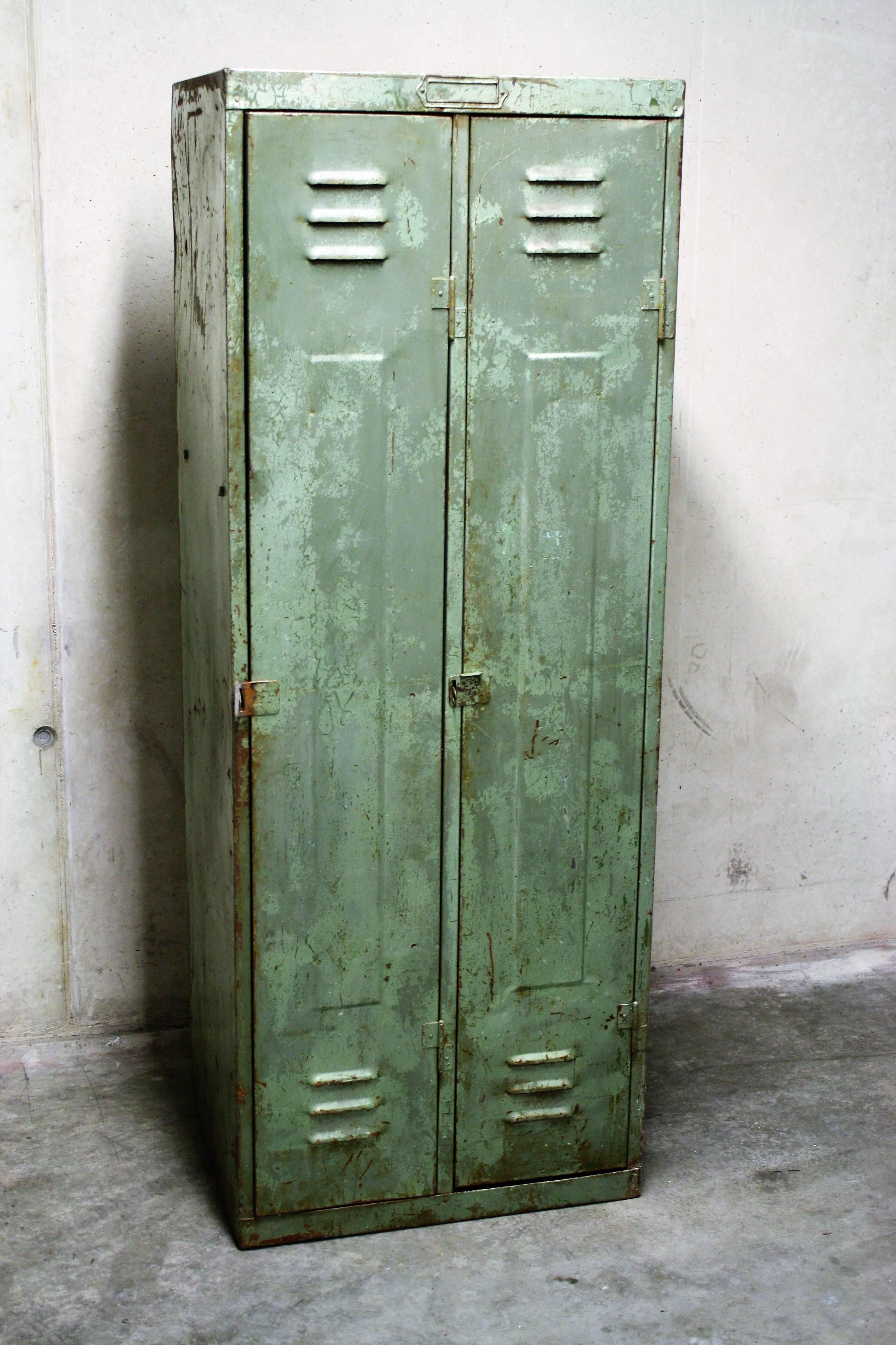Green Industrial locker cabinet with two doors.  
  
The wear and tear is instantly striking and gives this piece it's charming character.
  
We have some options for this cabinet. We can either provide four glass or metal shelves so it has in