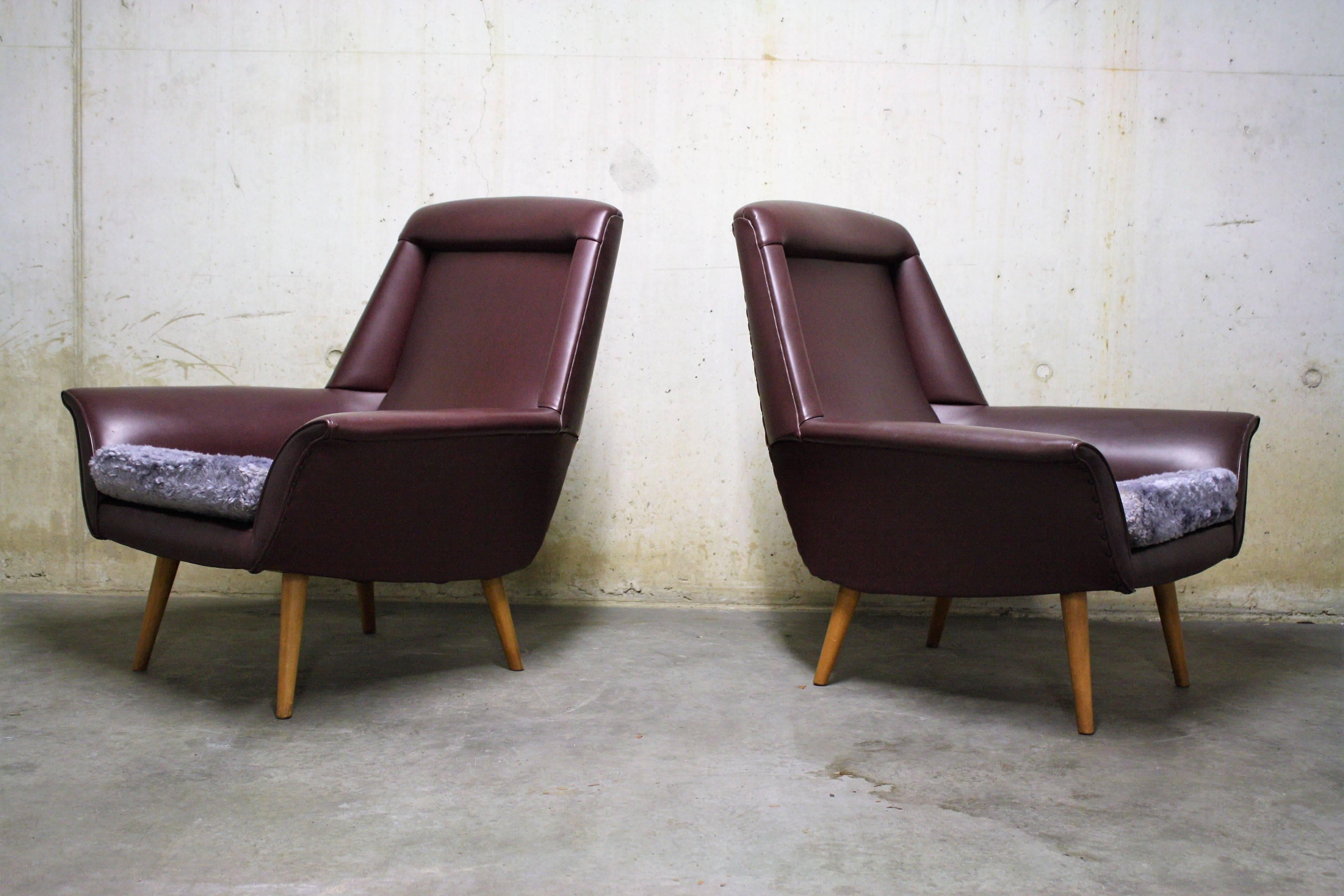 A pair of purple cocktail chairs made from skai. The cushions are not original and can be changed to something more 'civilized'.

These chairs are in a good condition and seat well.

The wooden legs combined with the bended armrests make the