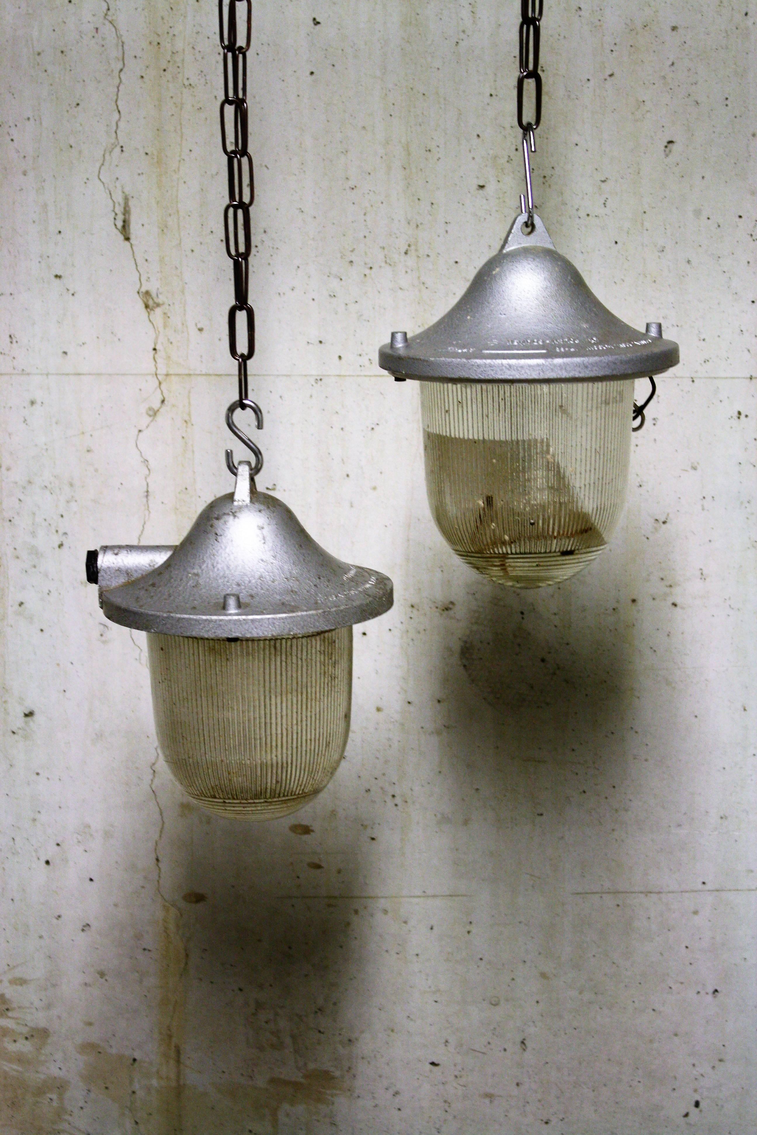 Vintage Industrial pendant lights made from cast iron and explosion proof prismatic glass.
?
These lamps are referred to as bully lamps or bunker lamps. 

They where commonly used in chemical fatcories, mines,.

These salvaged lamps have a