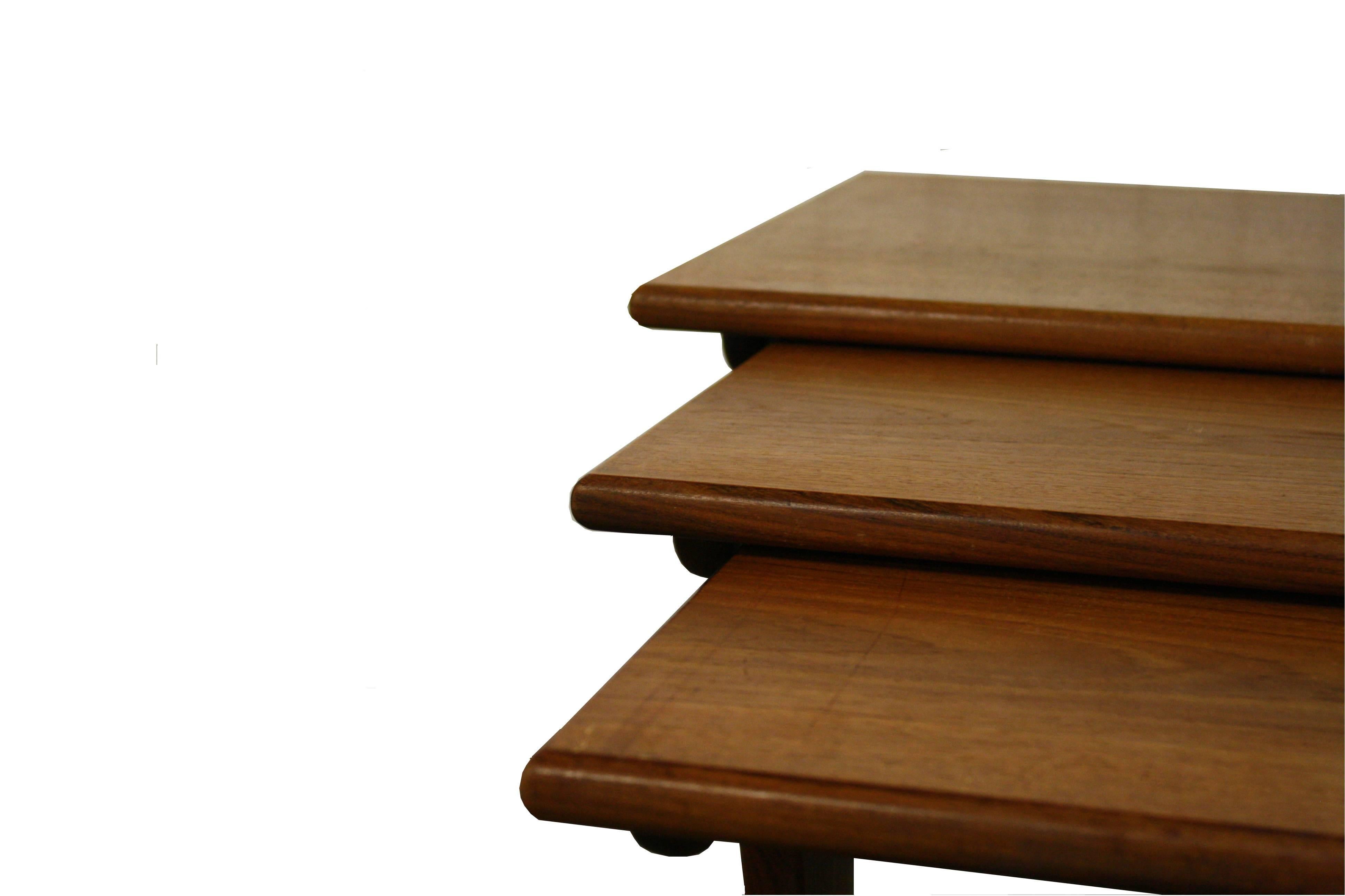 G Plan nest of three tables from the E Gomme furniture manufacturer. Each top is teak veneered and finished with solid teak edging, and each solid teak base has two stylishly fashioned pedestals which are connected by a curved stretcher.