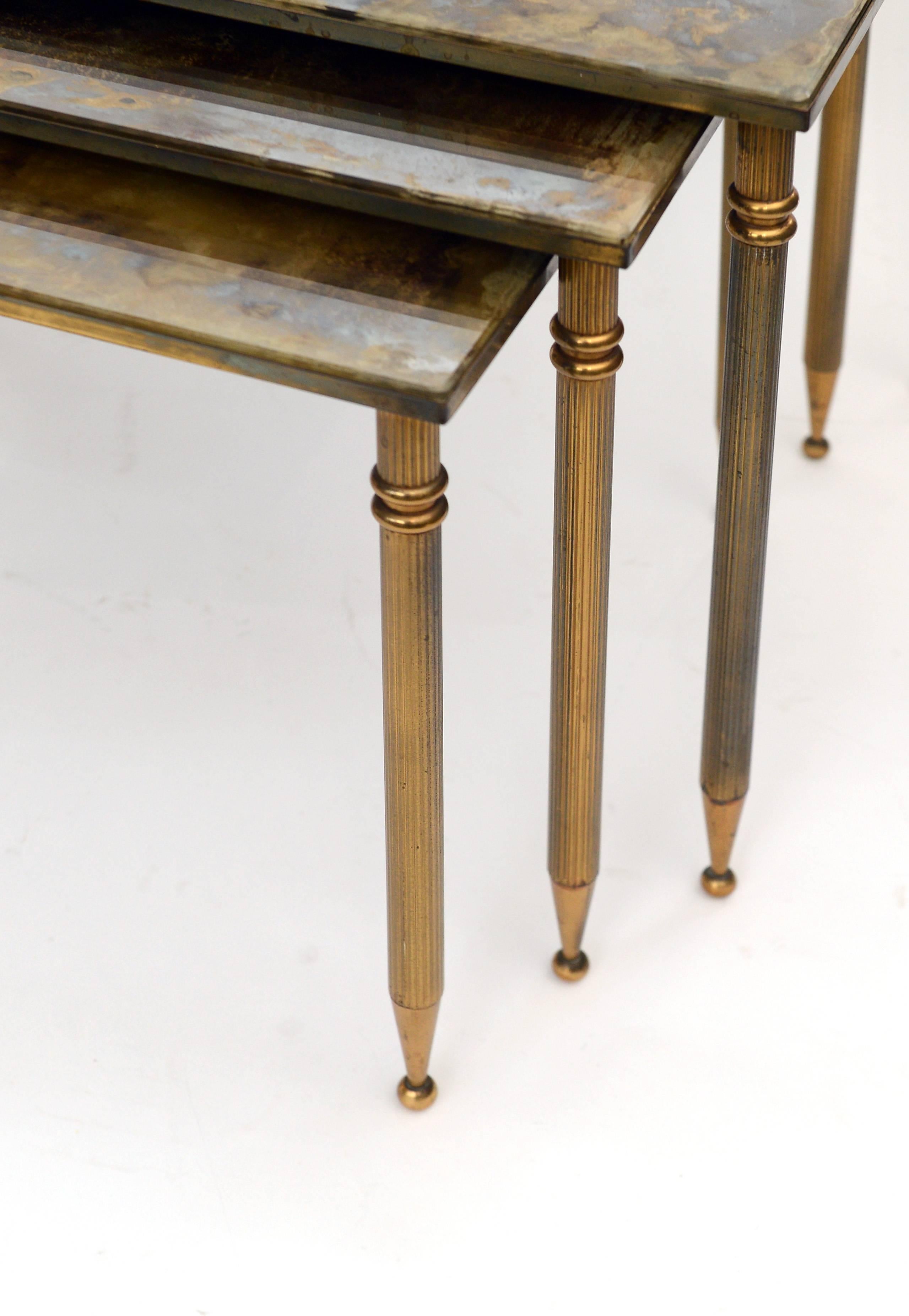 A set of elegant brass neoclassical nesting tables with dark patinated glass tops.

The whole set has a beautiful 'aged' look.

The glass of the largest tables shows some scratches.

Maison Jansen, maison bagues style.

1950s - France

The