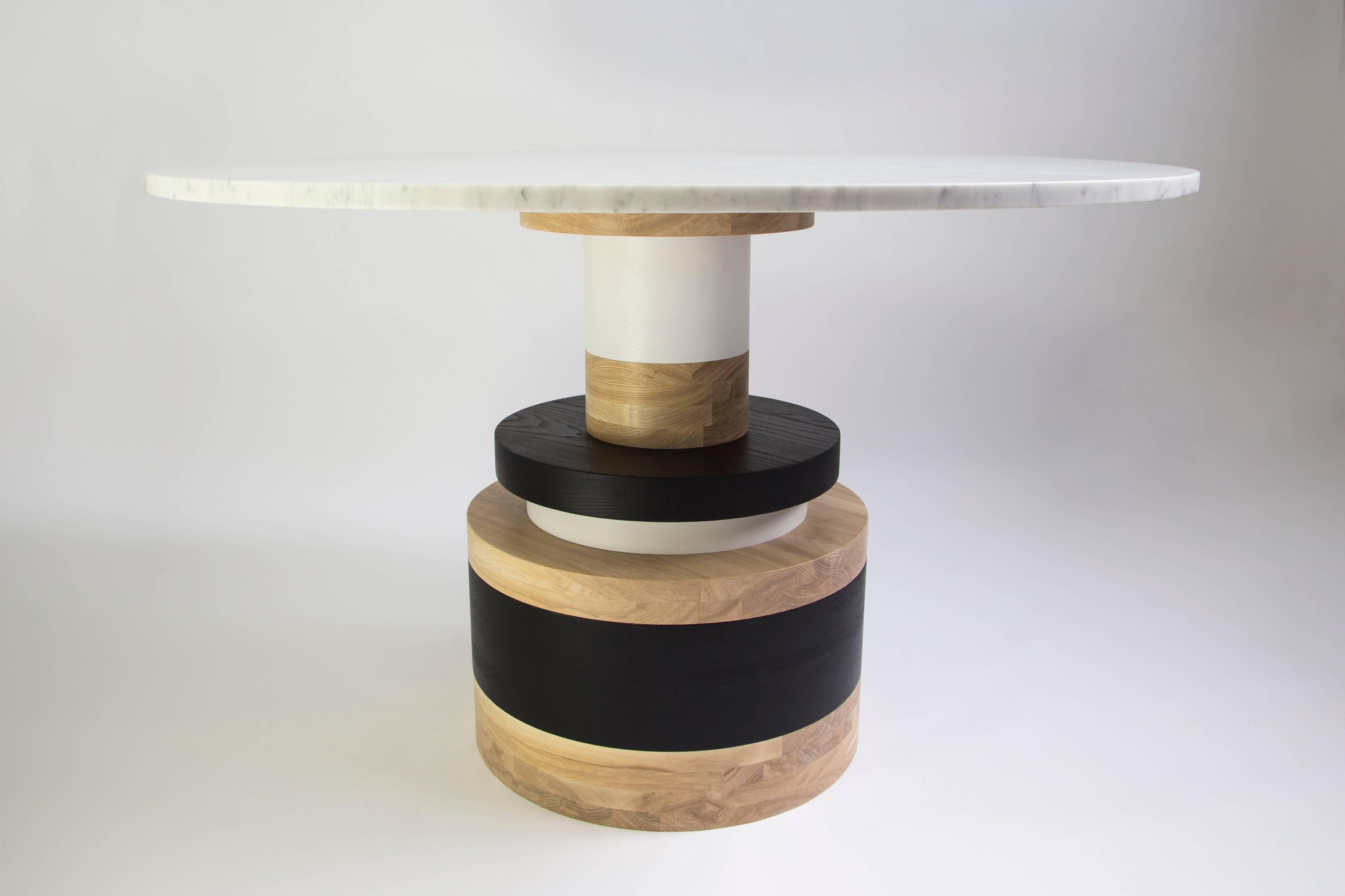 The Sottsass-inspired “Sass Dining Table” is a bold, graphic statement piece. A polished Nero Marquina marble top sits on an Amish-made base composed of painted and stacked wood circles. 

The version as shown is 54