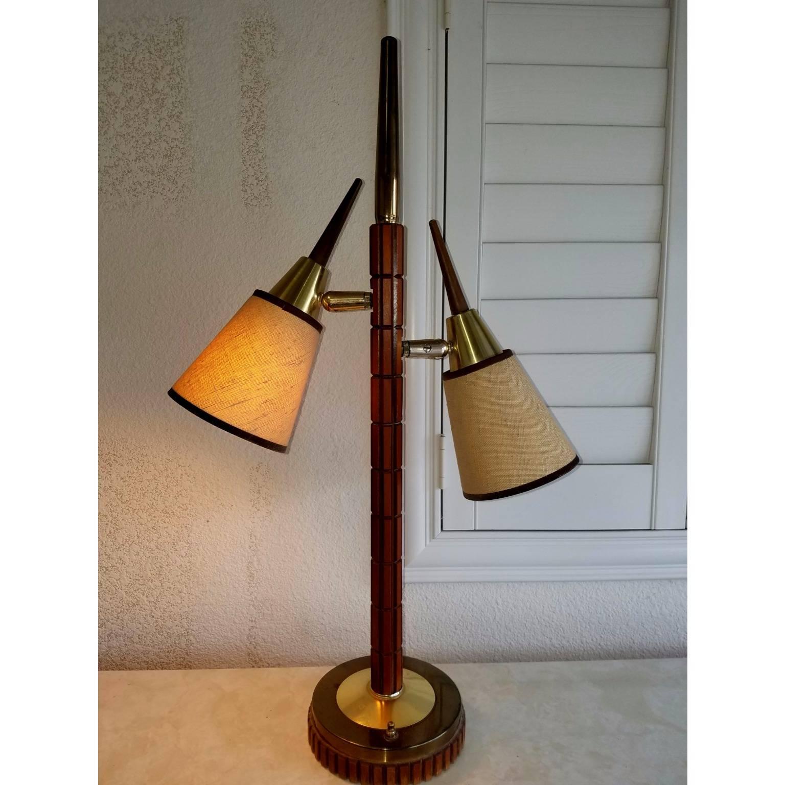 This table lamp is made out of wood and metal. It has two lights facing either direction. You can point the shades around from left to right. This lamp would be great in between two twin beds. Great condition. There is one picture where there is a