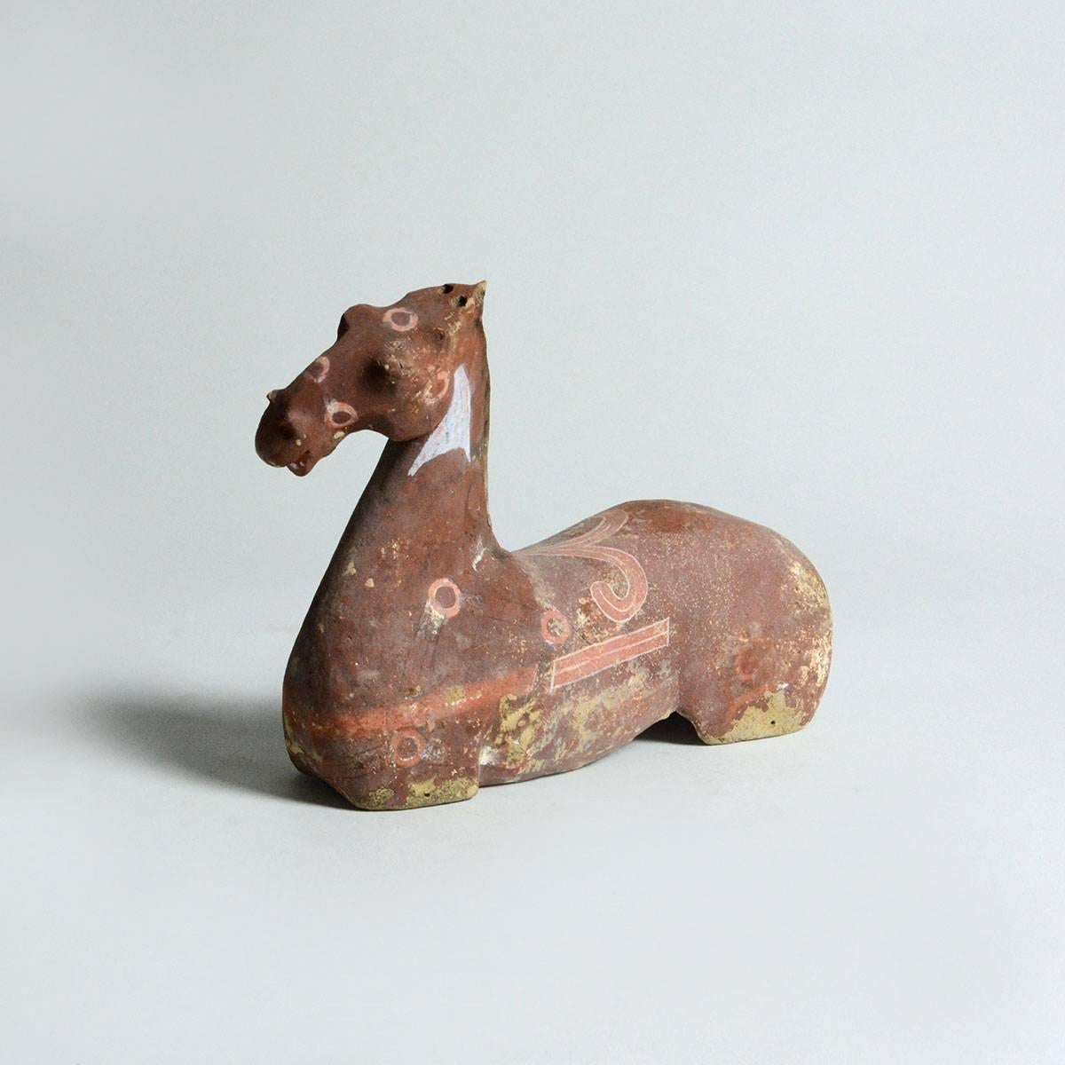This pottery figurine is sculpted to show the strong, bold line and muscularity of the horse. Once part of an assembled set, this horse bears the characteristics associated with the famed Heavenly Horse of Fergana. Its long muscular neck, arched