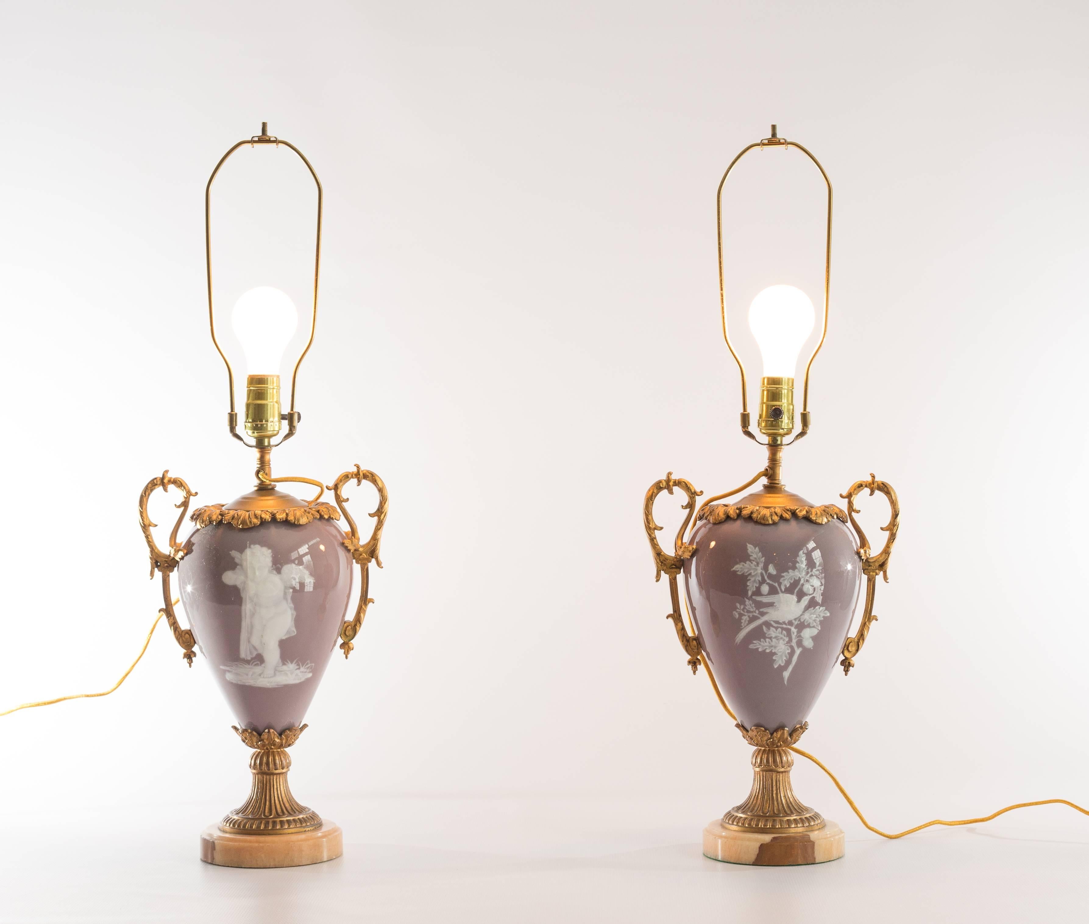 Pair of lavender Pate-Sur-Pate ceramic lamps with cupid or bird design, bronze trim handles, marble bases and silk shades, circa 1930. Measures: 10x21