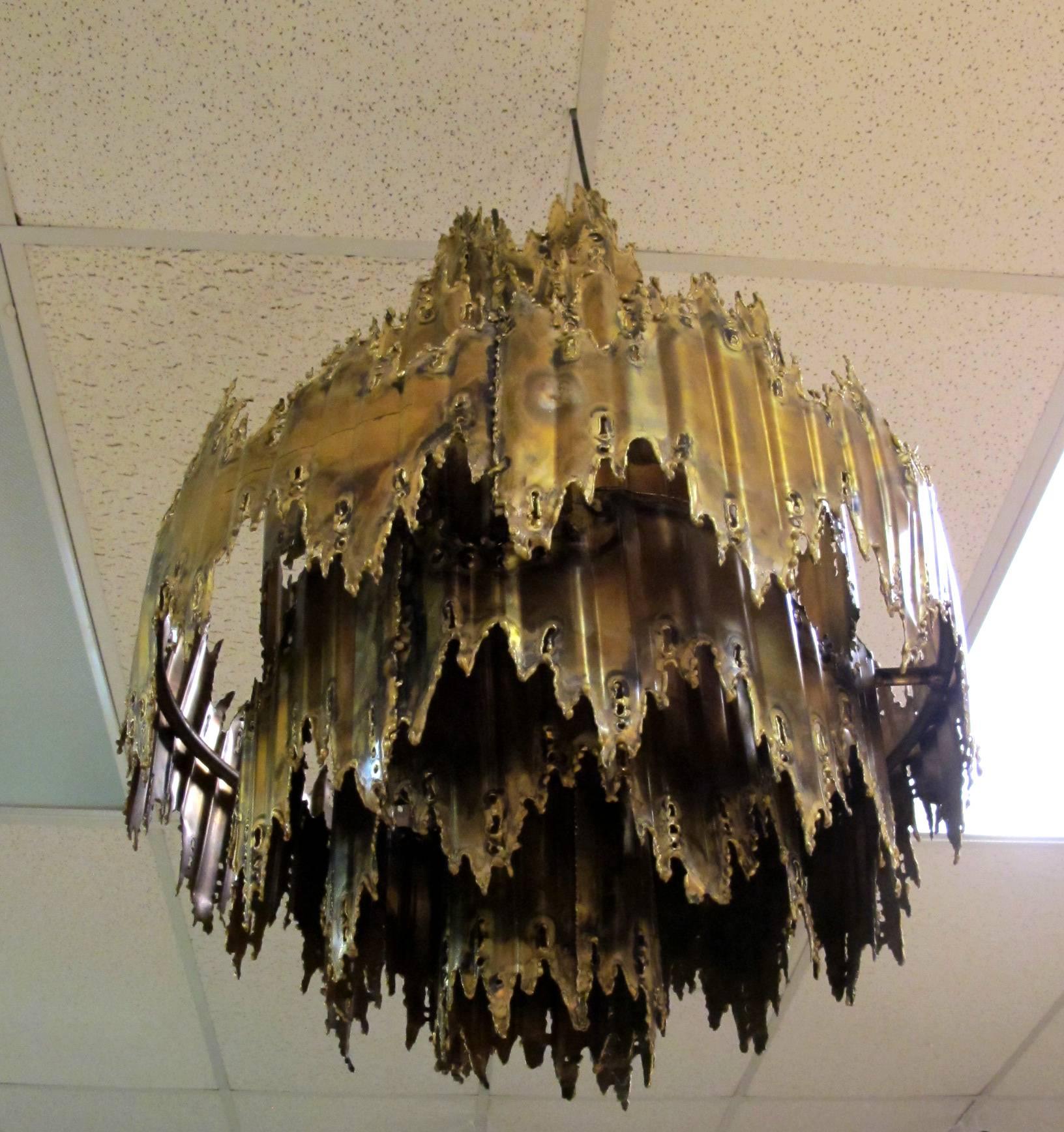 This very unique chandelier is made from plasma torch 
cut brass and copper. It is attributed to Tom Greene. It hangs approx 28