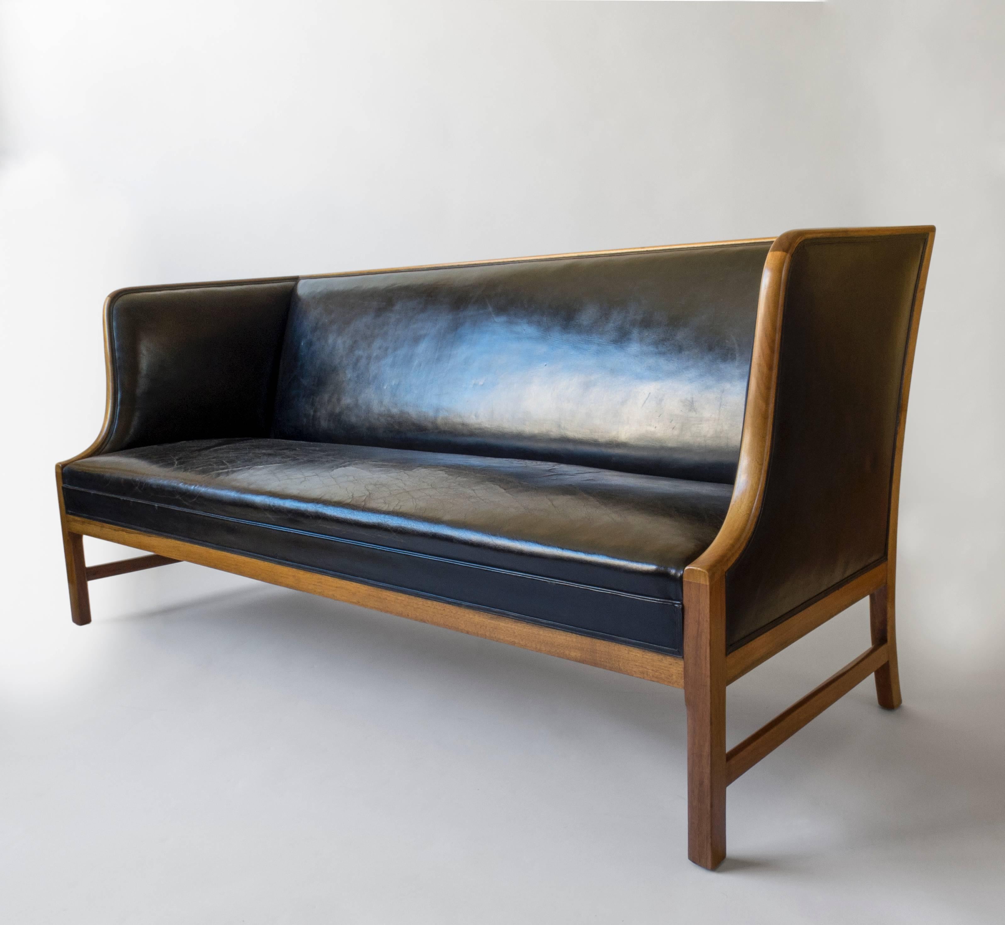 An understated and elegant design, deftly executed by premier master-cabinetmaker A.J. Iverson. Displaying a radiant and beautifully aged golden walnut frame that has been finely restored. 

The linear toprail, issuing two gently unfolding side