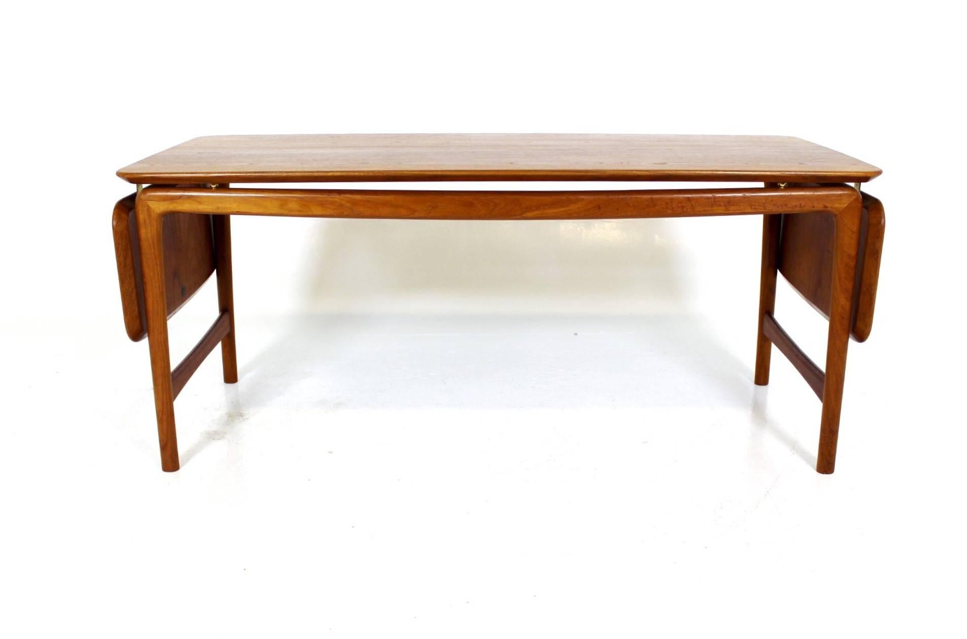 Teak coffee table designed by Peter Hvidt & Orla Mølgaard Nielsen for by France & Daverkosen in the 1950s. This coffee table is made from solid teak wood with foldable side leaves and brass hardware.
Measures: W= 129 +26.5 +26.5 = 182 cm
D=