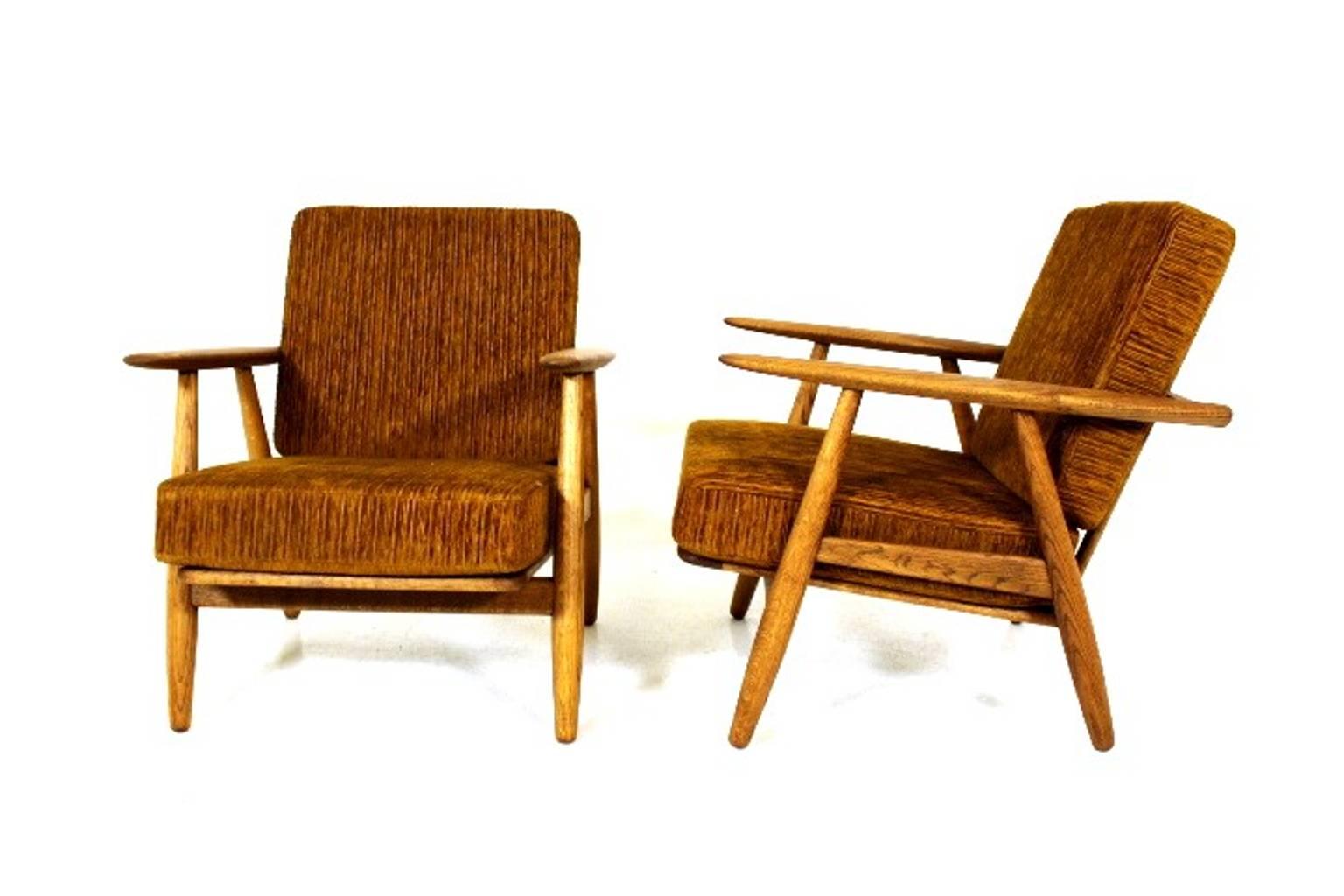 A pair of Hans J Wegner cigar lounge chairs model GE 240 in oak and fabric.
         