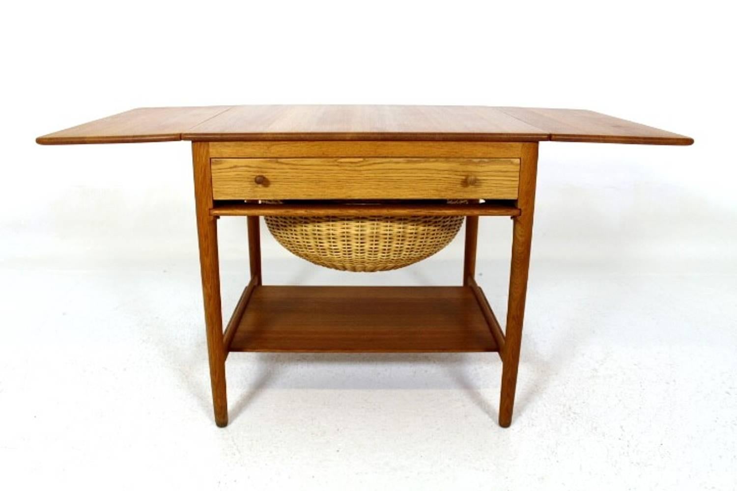 Hans J. Wegner sewing table in solid oak with two drop-leaves, front drawer and a woven cane basket. Designed by Hans J. Wegner 1959. Manufactured by Andreas Tuck. Model AT-33. This is an early production with the solid top.
Measures is W = 64.5 +