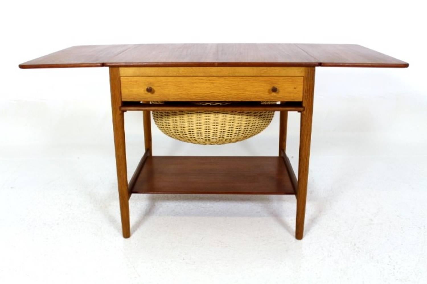 Hans J. Wegner sewing table in teak and oak with two drop-leaves, front drawer and a woven cane basket. Designed by Hans J. Wegner, 1959. Manufactured by Andreas Tuck. Model AT-33. Perfect as a side table.
Measures is W = 64.5 + 27 + 27 cm.