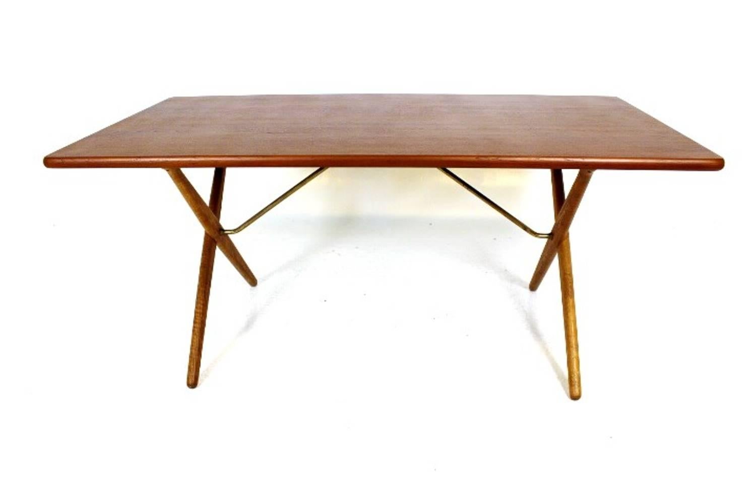 Great dining table can also be used as a writing desk, designed by Hans J. Wegner, model AT-303. Manufactured by Andreas Tuck. Top in teak and legs in solid oak with brass trust base. Stamped with designer and maker. See pictures for condition.
 