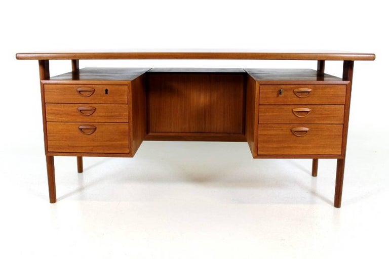 Freestanding executive desk with a floating top. Designed in 1958 by Kai Kristiansen, Model FM60, produced by Feldballes Møbelfabrik in Denmark. Made in teak and with tapered legs.
The back of the desk has three storage compartments, so the desk
