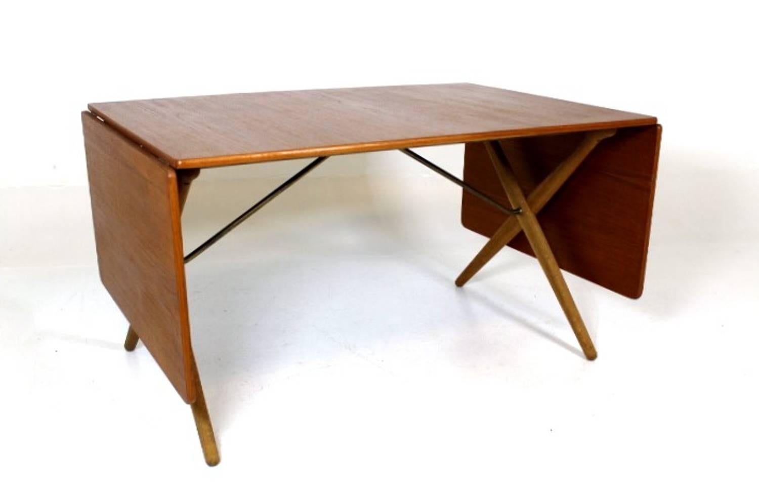 Great dining table, designed by Hans J. Wegner 1952, Model AT-309. Manufactured by Andreas Tuck. Top in teak and legs in solid oak with brass trust base. Stamped with designer and maker. 
Measures: 128 + 50 + 50 = 228 cm long.
