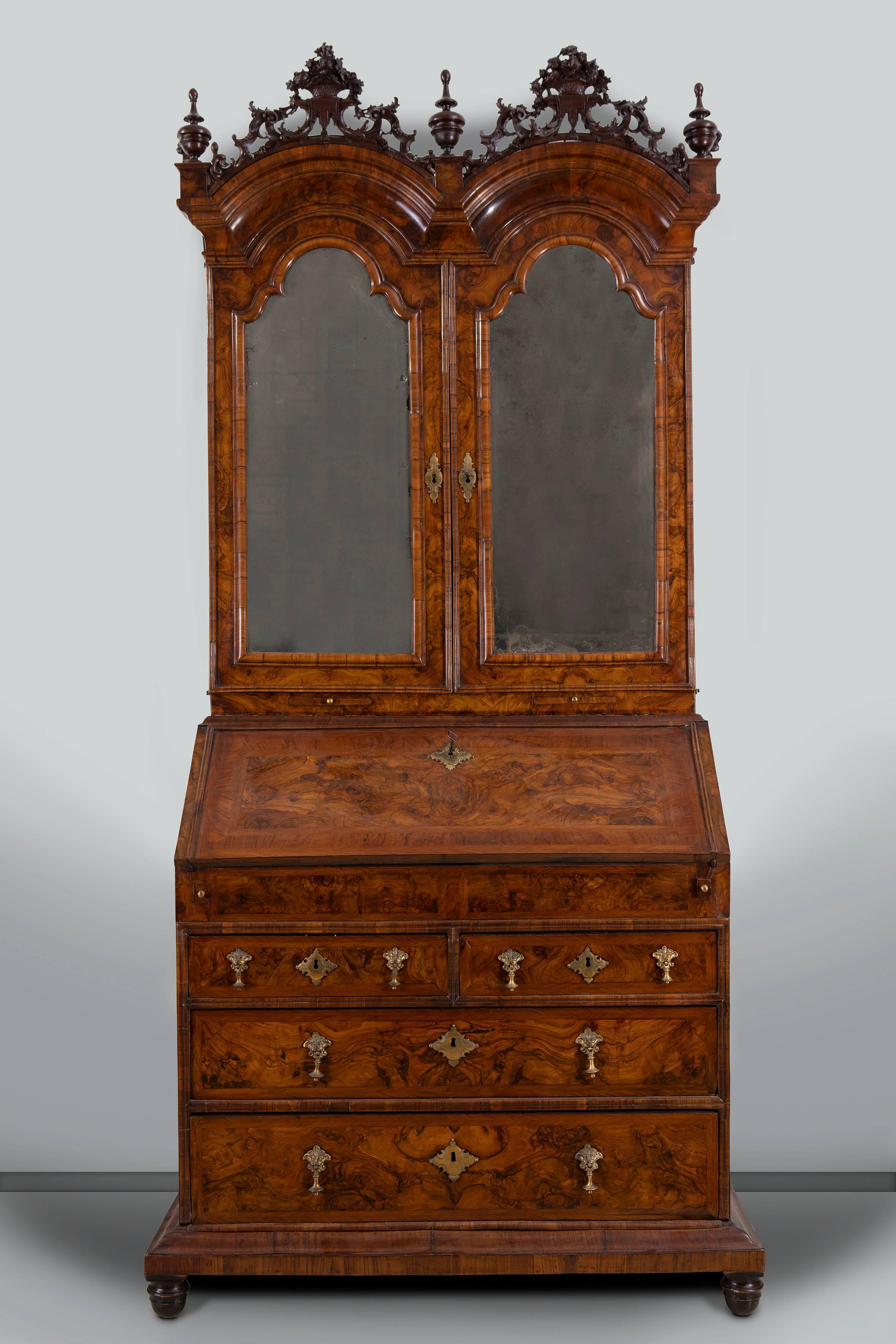 North Italian walnut bureau cabinet inspired to English bureau cabinets, Veneto, second quarter of the 18th century

Feather-banded overall, the double-domed cornice floral cresting divided by orb finials, above a pair of arched doors with