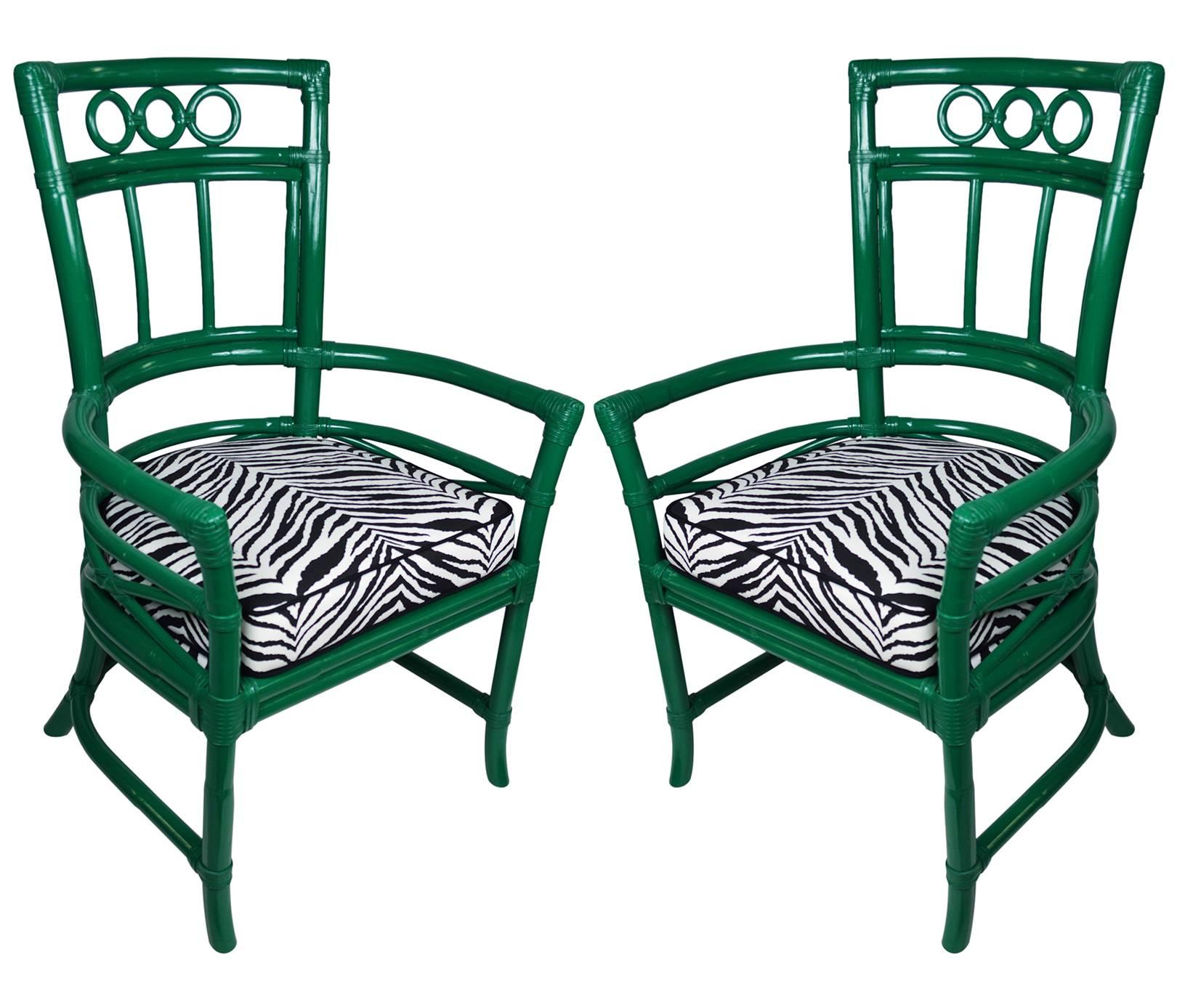 Pair of Ficks Reed armchairs newly lacquered in a deep emerald. The rattan frames are adorned with decorative circles and leather windings. The seat frames and new cushions are upholstered in a zebra print with black piping.