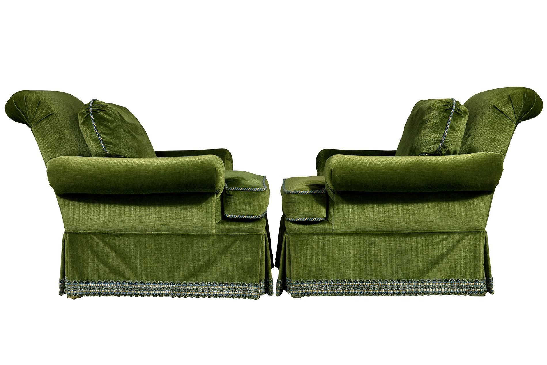 Pair of armchairs upholstered in a rich green Scalamandre velvet with rolled arms and backs. The chairs have skirts and Houles tape and cording with removable cushions.