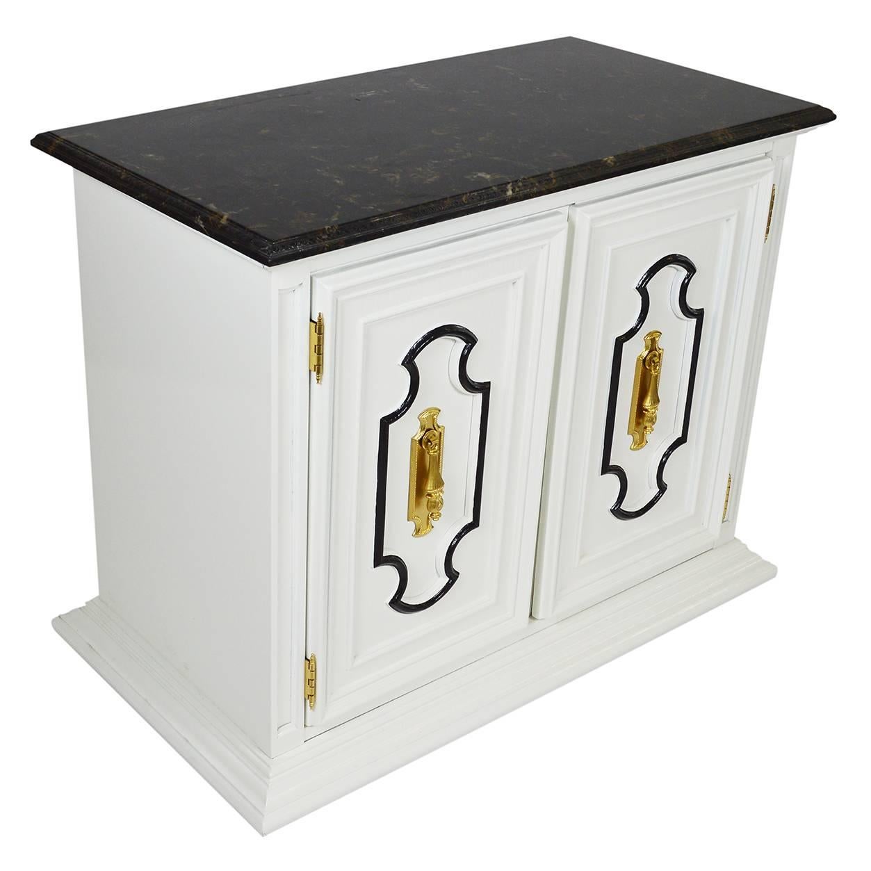 Vintage Midcentury marble-top bar cabinet. The cabinet is crafted in a Dorothy Draper-style and is newly lacquered in white with black trim and brass hardware and mounted on castors for easy movement. Inside the double cabinet doors is a shelf and