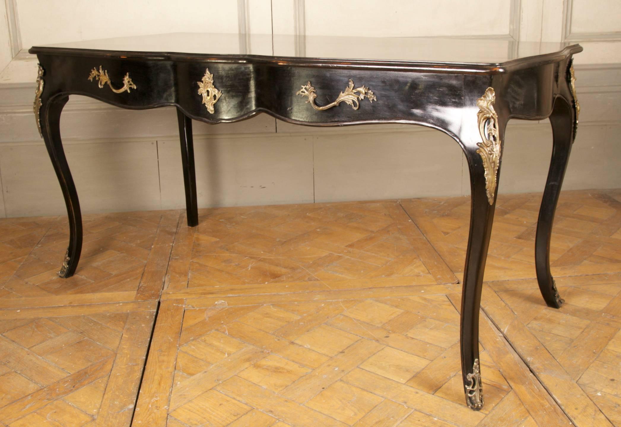 Louis XV style bureau plat, freestanding design with brass ormolu on both sides and three drawers. This design is also used as a vanity table. Hand-carved in solid beech and hand finished in a black lacquer patina. This piece can also be ordered to