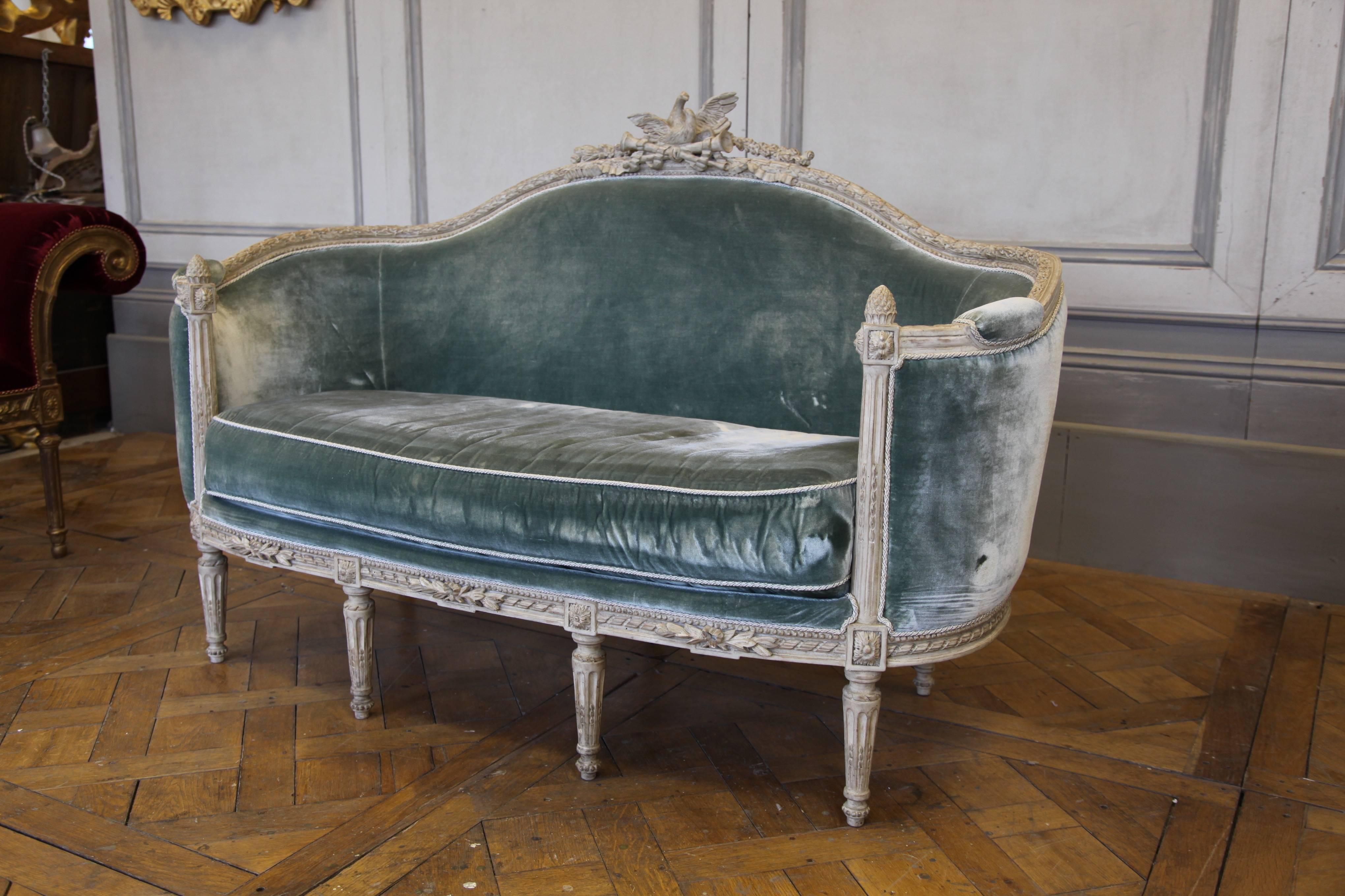 Louis XVI style Corbeille sofa: Hand-carved by master craftsmen and hand finished in a lightly aged and distressed, gesso, cerused patina made using traditional methods and materials. Upholstered in blue-grey silk velvet as seen in the picture.
   