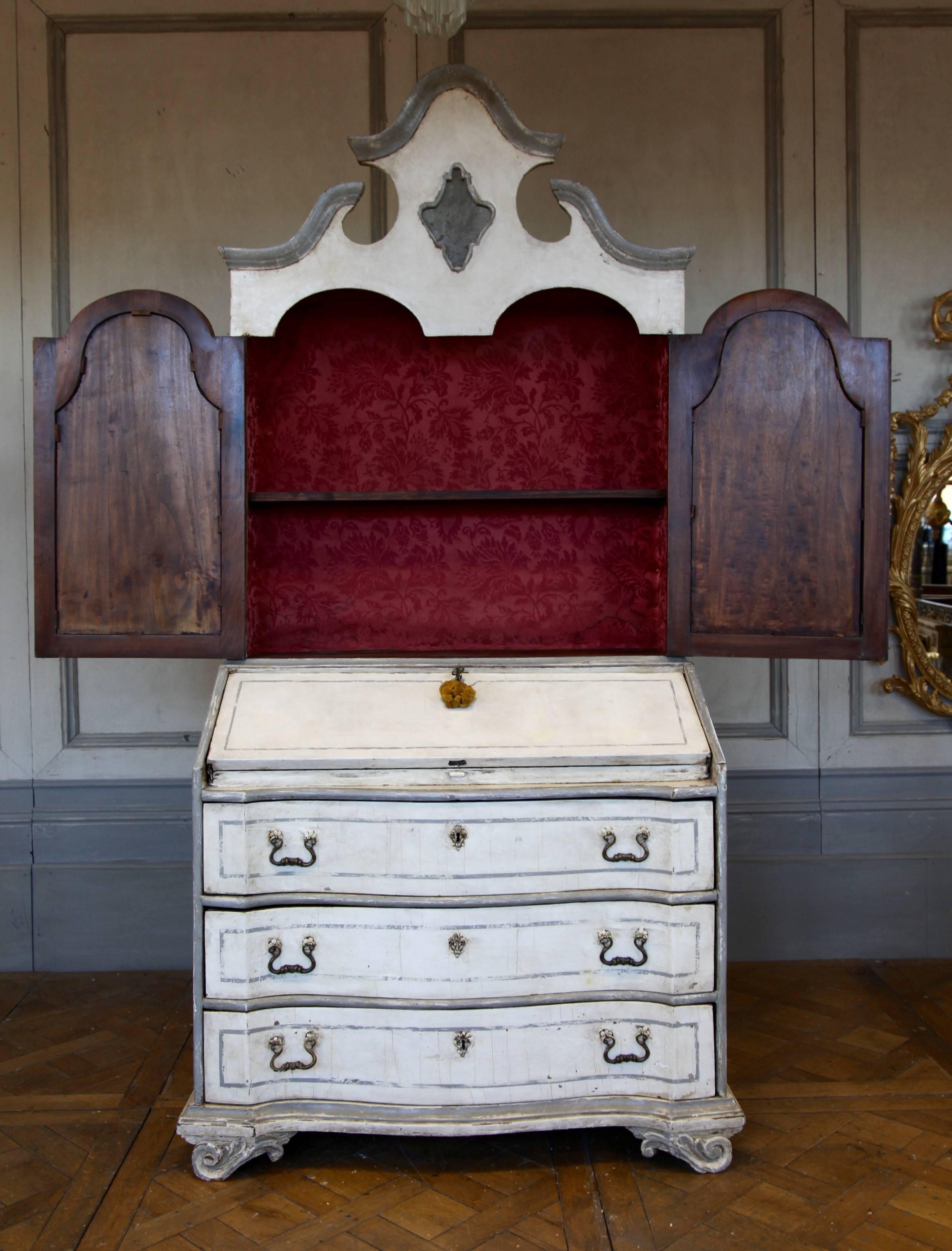 18th century, Rococo period, Italian Scriban. Painted in two-tone finish with aged patina. Interior lined with claret red damask. Comprise of a chest with three drawers, the top of the chest opens into a writing desk and the top cabinet has one