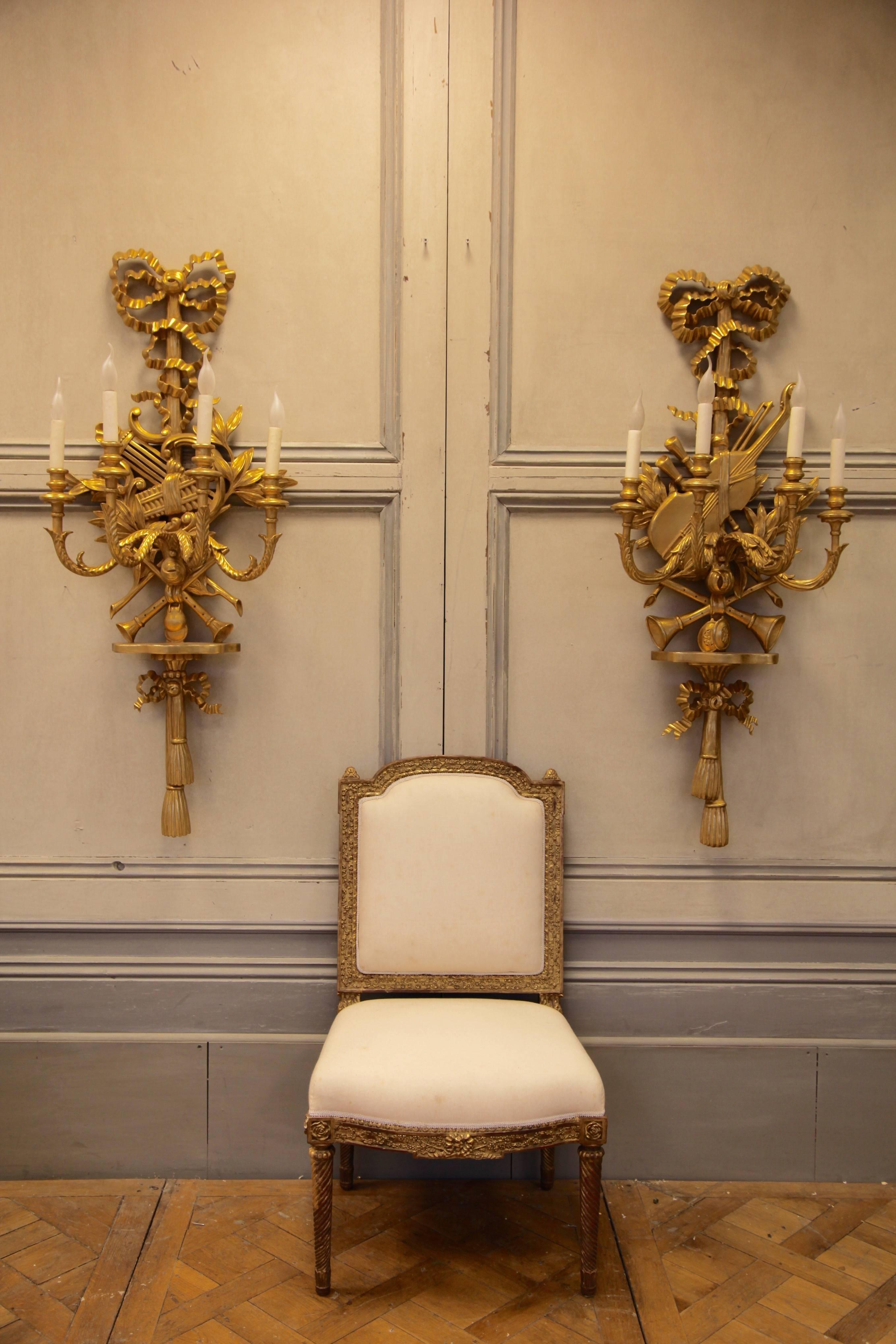 Exceptionally crafted, very large, Louis XV Style, pair of hand-carved wall lights. Hand Gilded in antique gold finish. Featuring traditional motifs of musical instruments, laurel leaves and interlacing ribbons.