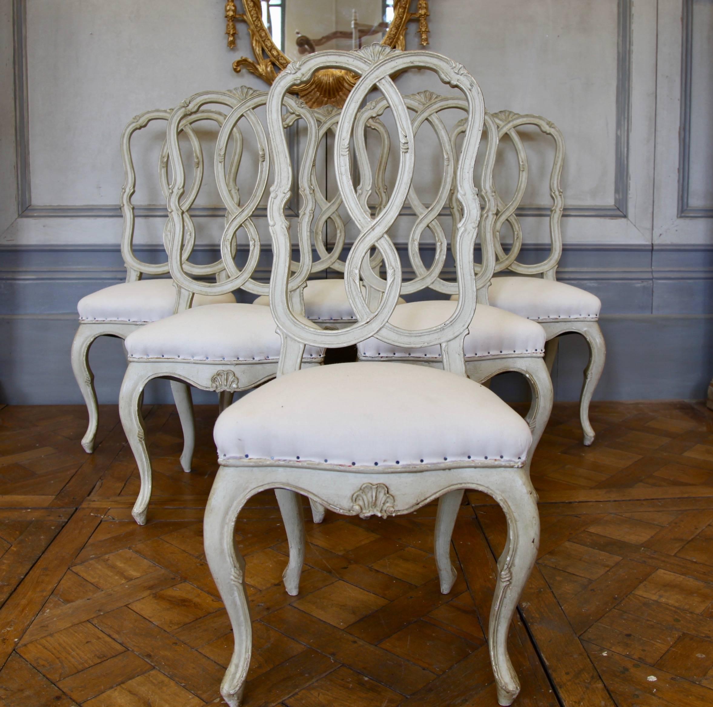 19th century set of dining chairs,
with elegant scrolled back , painted in a light warm grey.
Covered in Calico, ready to be covered.
 