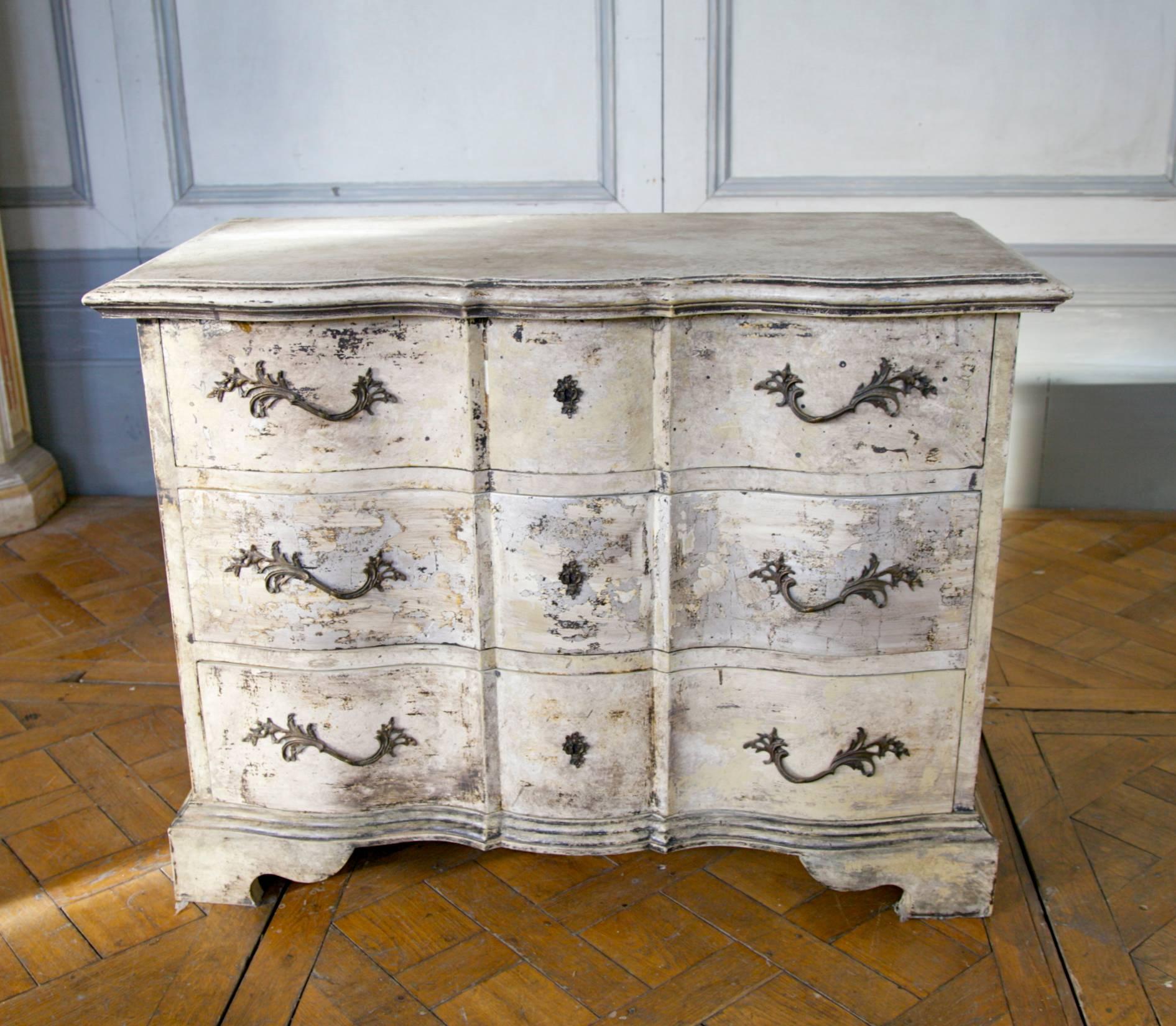 Hand-carved Louis XIV style Arbelette chest of drawers. Hand finished in a textured two tone patina of distressed paint work over silver gilding.