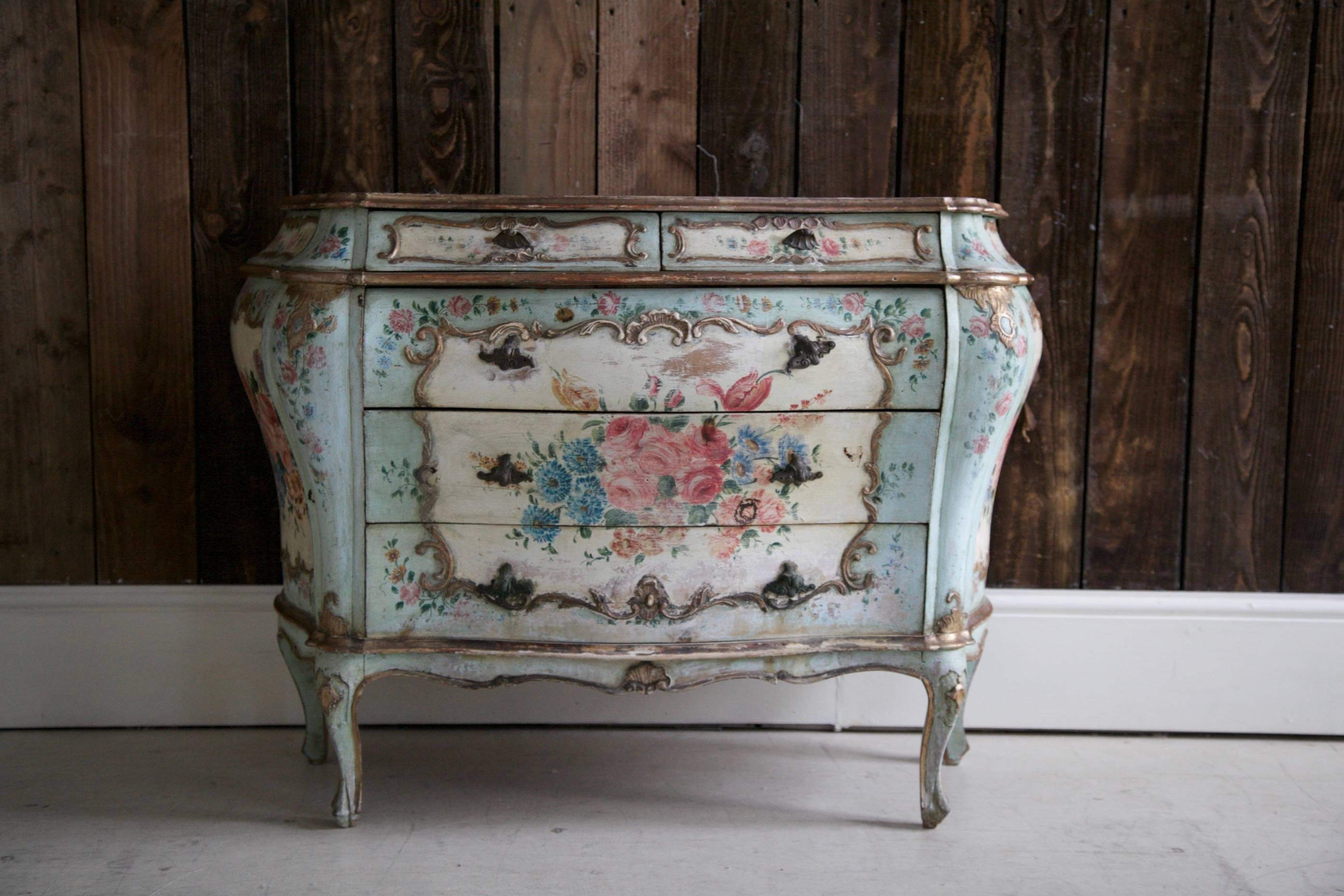 Bombe style, 19th century. Italian chest of drawers painted in the Venetian style, depicting floral motifs, highlighted with gilded raised areas. Bronze casted handles styled in the shape of a shell.