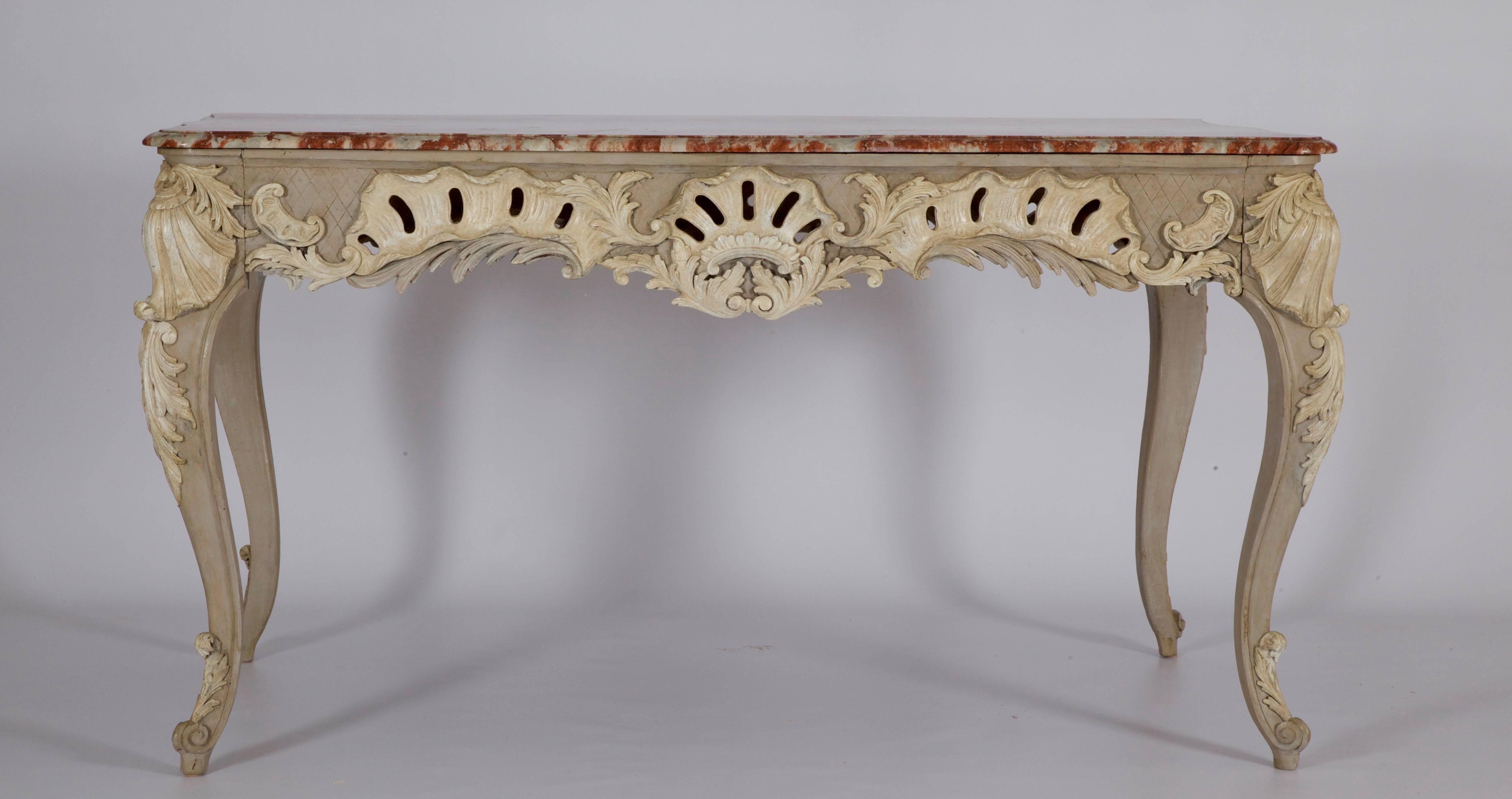 19th century, freestanding, centre table intricately carved on all sides with Louis XV style motifs. Finished in a two tone patina of French grey with Ecru white highlighting. The piece is topped with the original, beveled and shaped, Pyrenean red