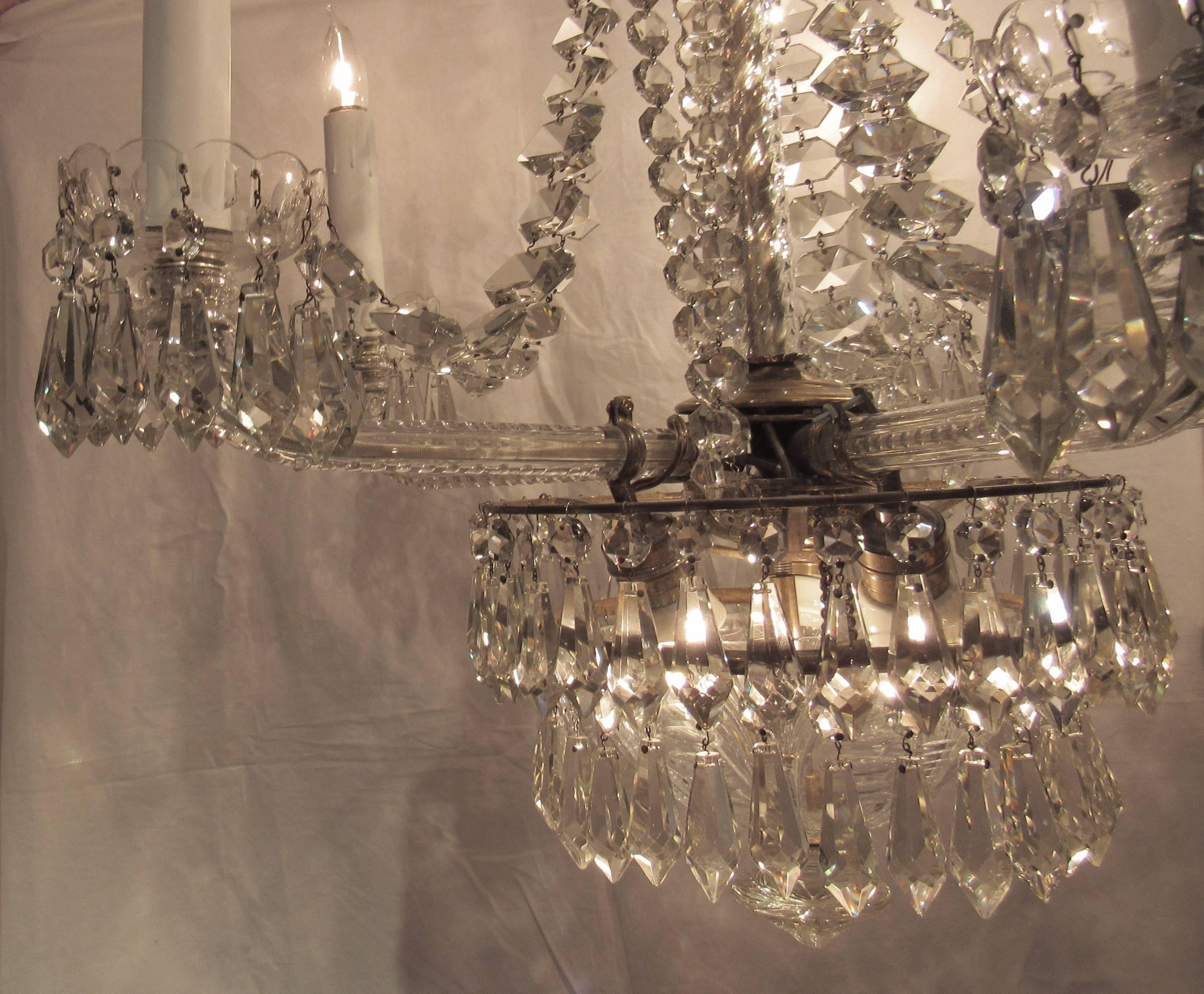 Beautiful large crystal chandelier, early 20th century.

Five arms with cut glass rods. Glass dome in center with three lights surrounded by two graduating rows of prisms. Total of eight lights. Glass rod covers the central post with unusually