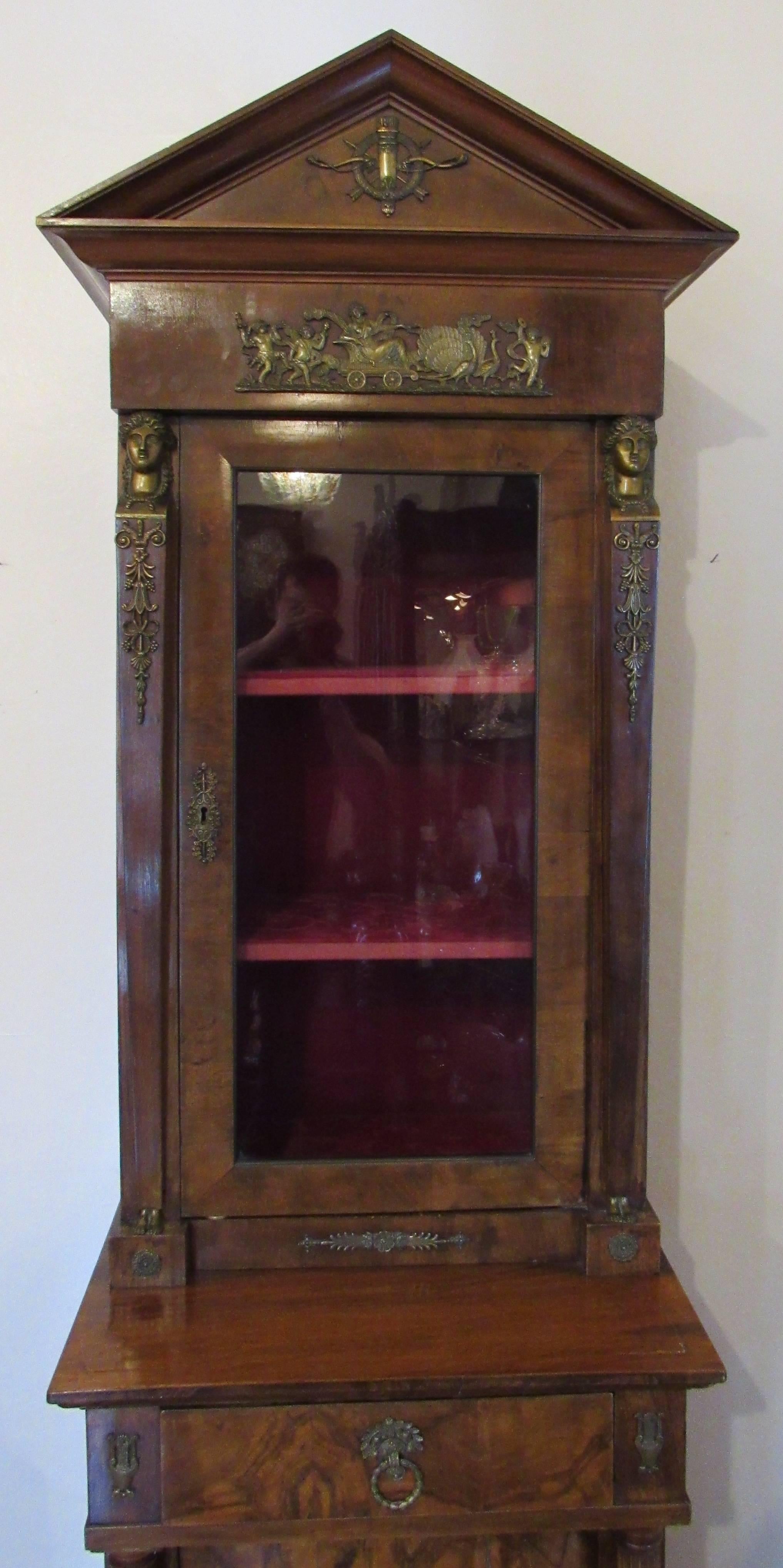 Lovely French Empire mahogany cabinet with classical ormolu mounts, 19th century.

Top section with red velvet interior and two shelves. Bottom cabinet with single rounded door with one interior shelf.

Measures: 82