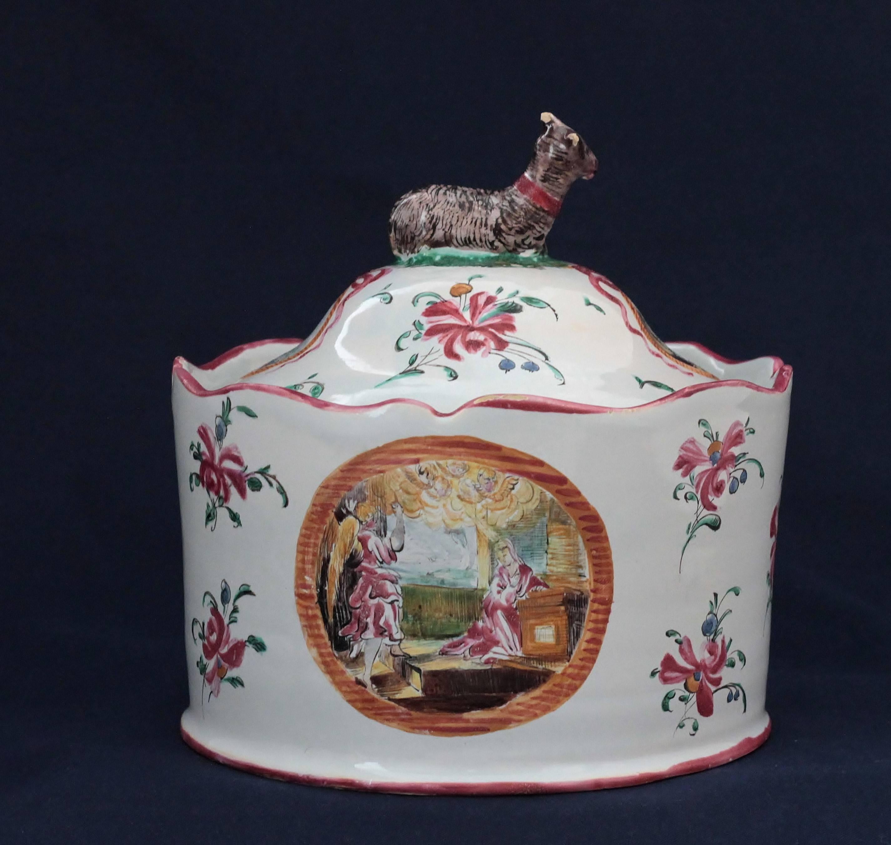 A Moustiers (France) covered round box in faience with a polychrome decoration of religious scene : The Annunciation and Saint Marie-Madeleine, and flowers. Goat on the lid. Factory of Fouques, circa 1780-1790. 18th century. Measures: Diameter 15